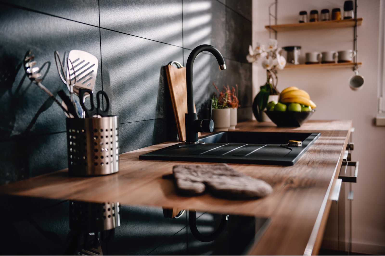 A kitchen with a sink and a bowl of fruit on the counter.