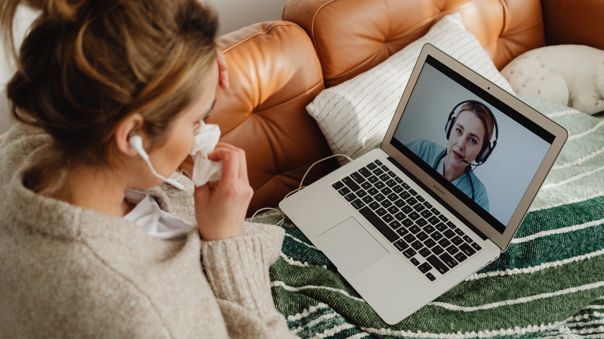 A woman is sitting on a couch with her head in her hands.