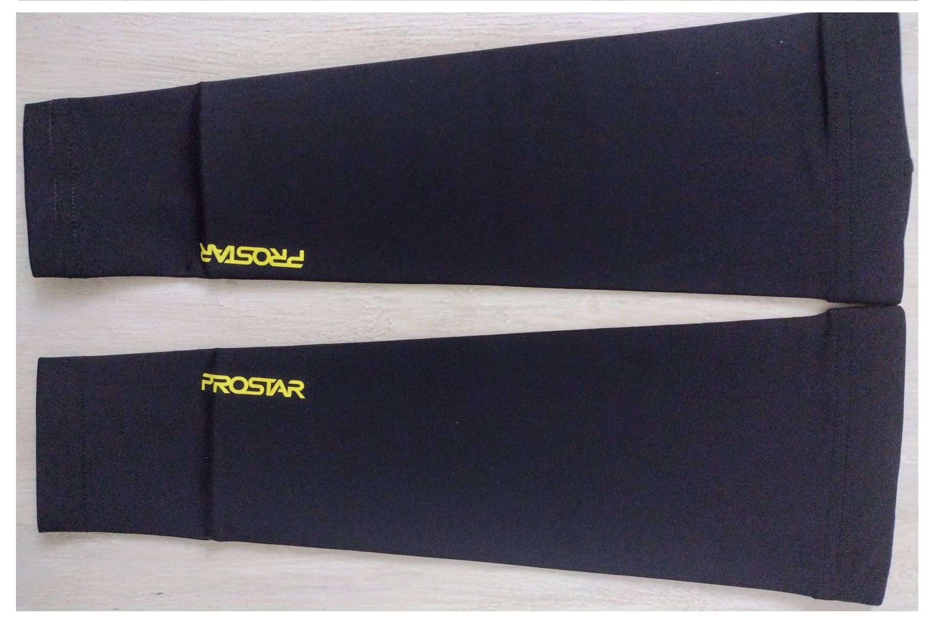 Un par de mangas deportivas negras para los brazos con el logotipo amarillo 