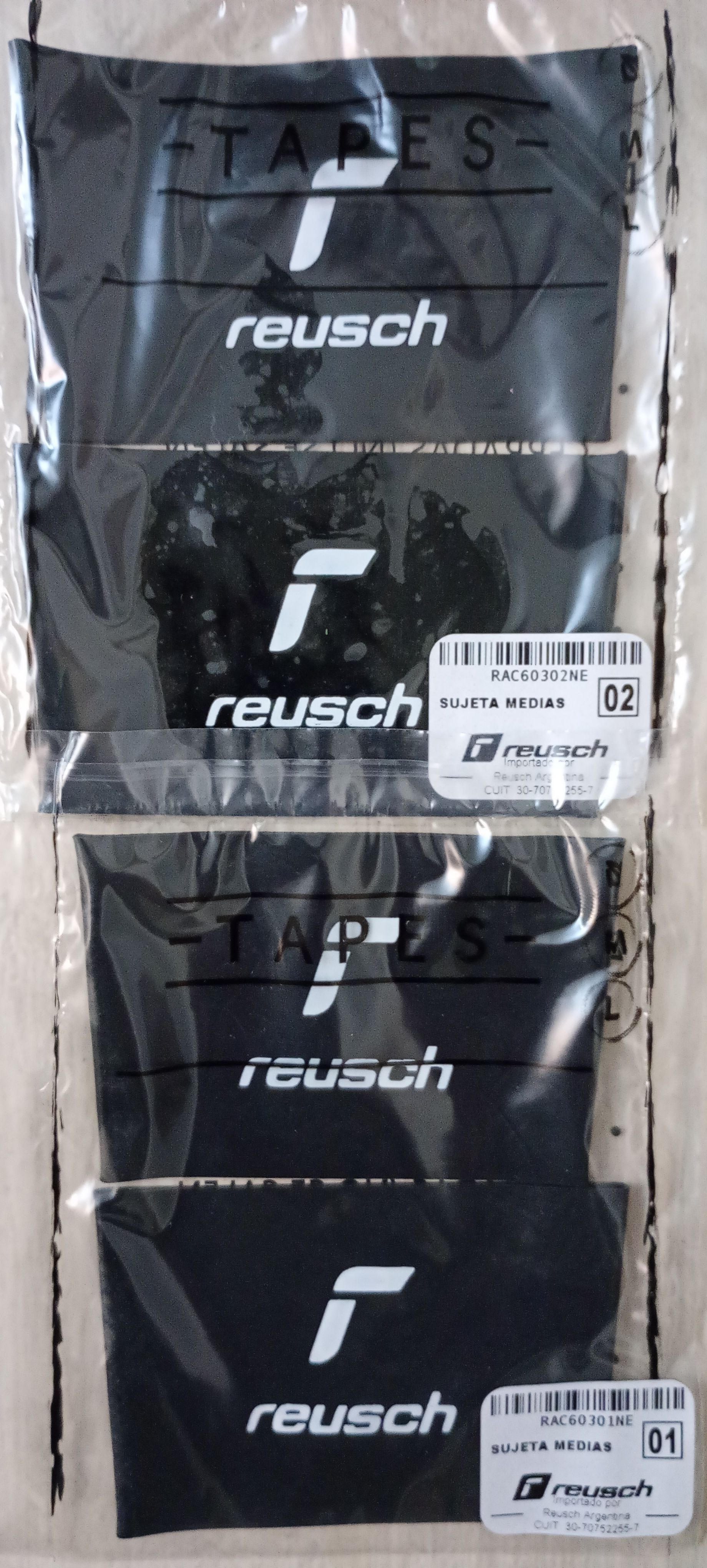 Dos pulseras negras de Reusch en un envase de plástico transparente, con el logotipo blanco de la marca y el texto 