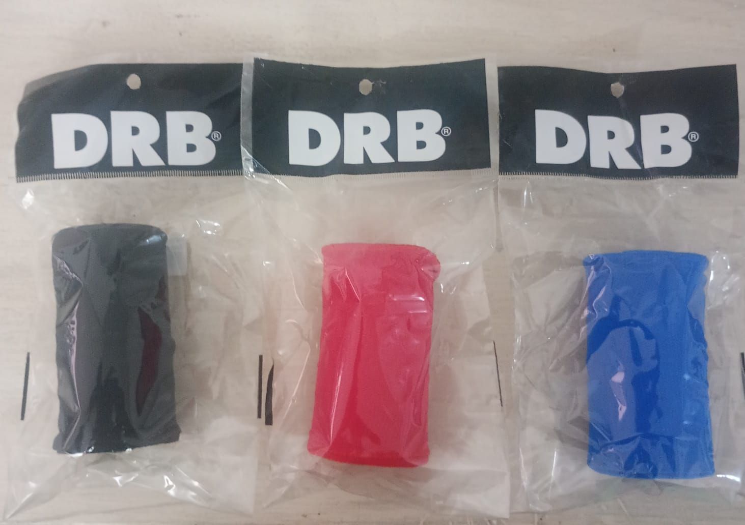 Tres cintas para el sudor de la marca DRB, empaquetadas individualmente y disponibles en negro, rojo y azul.