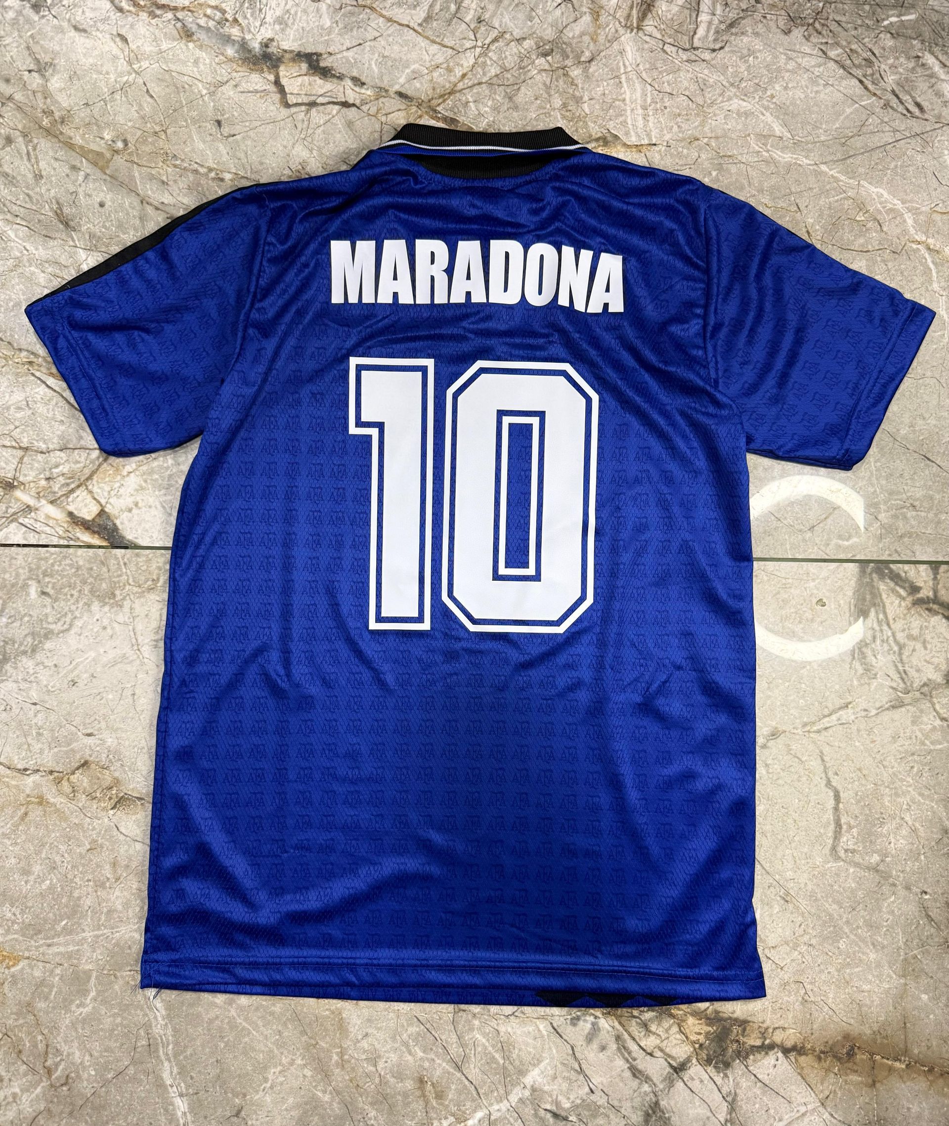Una camiseta azul de la selección argentina de fútbol con el número 10, cuello negro y una franja vertical negra estampada.