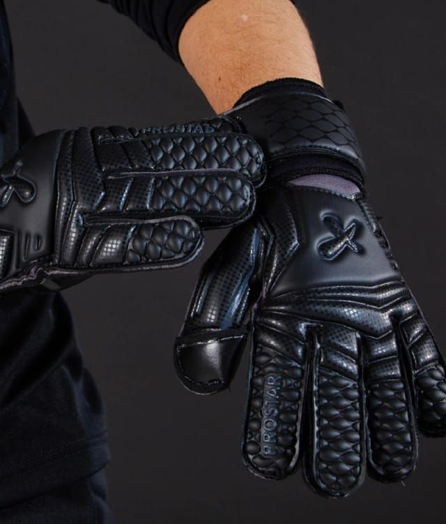Guantes de cuero acolchados negros en las manos de una persona, una mano abierta sobre un fondo oscuro.