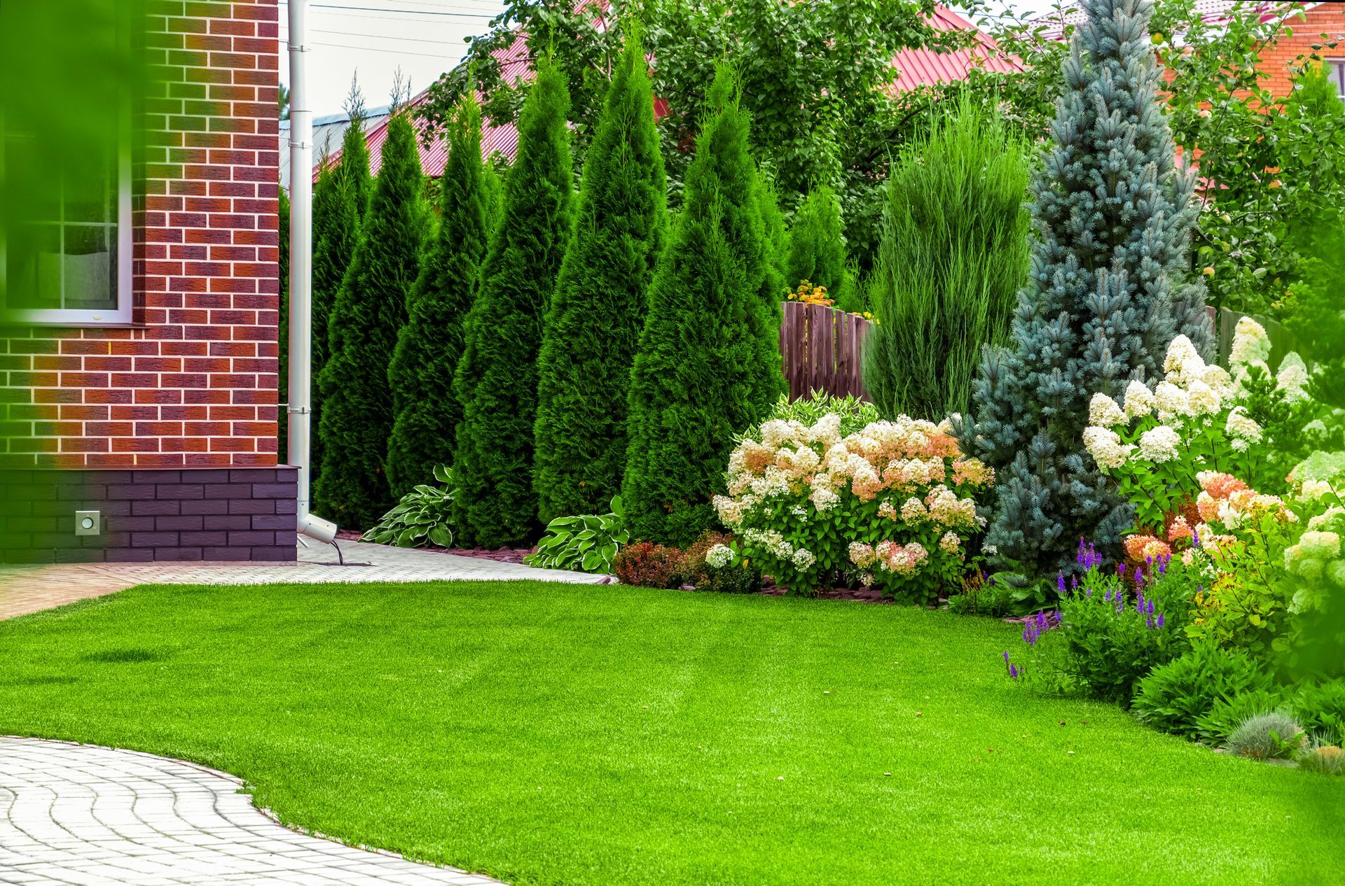 A Lush Green Yard with Trees and Flowers in Front of A Brick House - Kinston, NC - Garden Gator Landscape & Design A Lush Green Yard with Trees and Flowers in Front of A Brick House - Kinston, NC - Garden Gator Landscape & Design