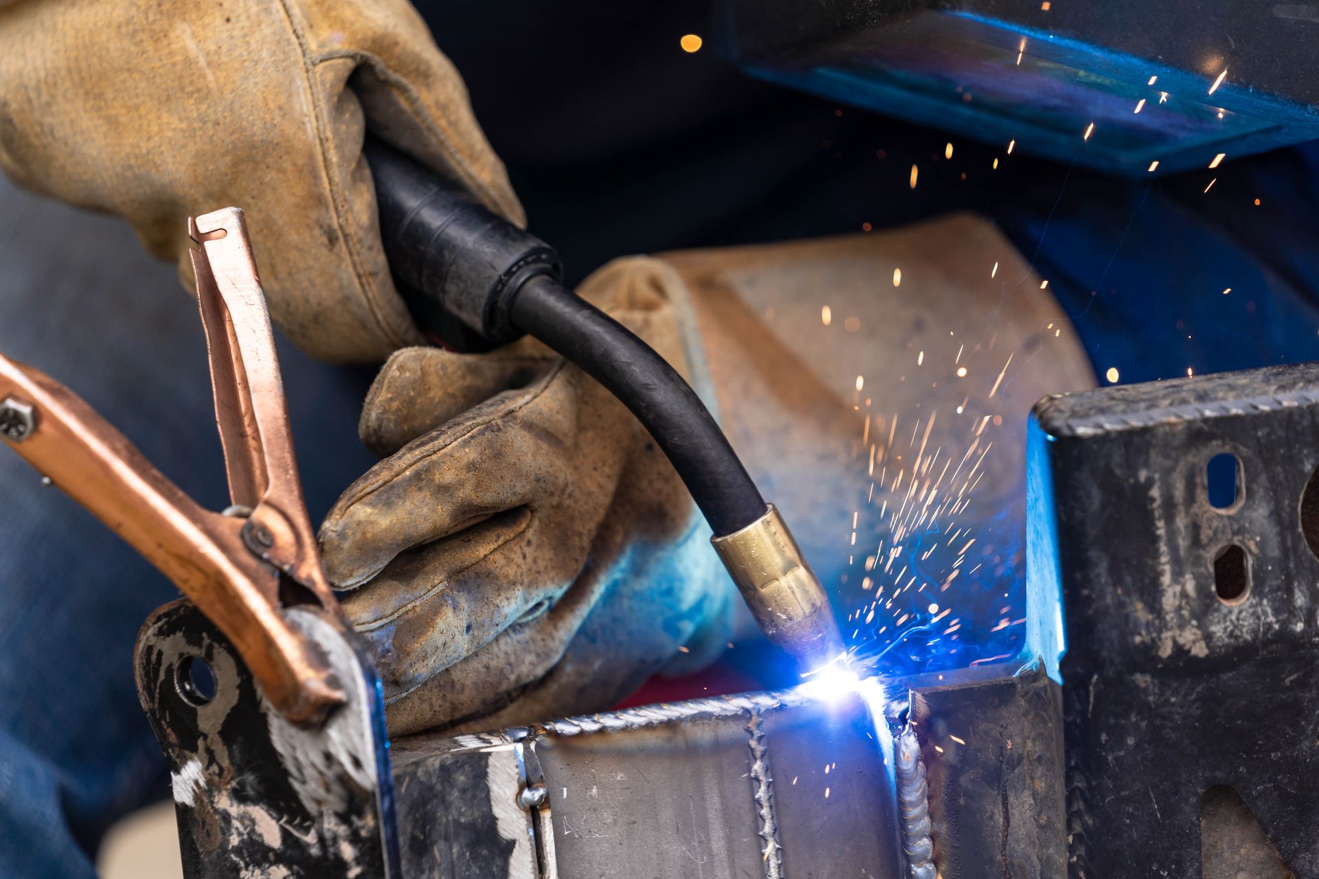 Welder in Gloves Using a Welding Torch on Metal, Creating Sparks — Bryants Laser Works in Ipswich, QLD