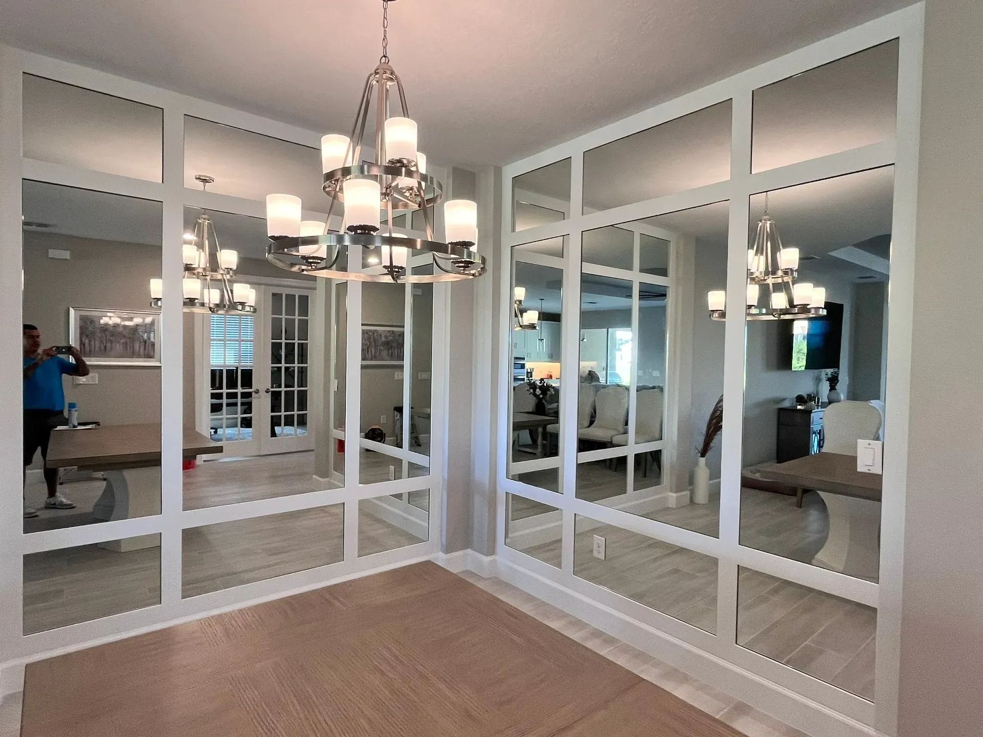Dining room with mirrored walls and a chandelier.