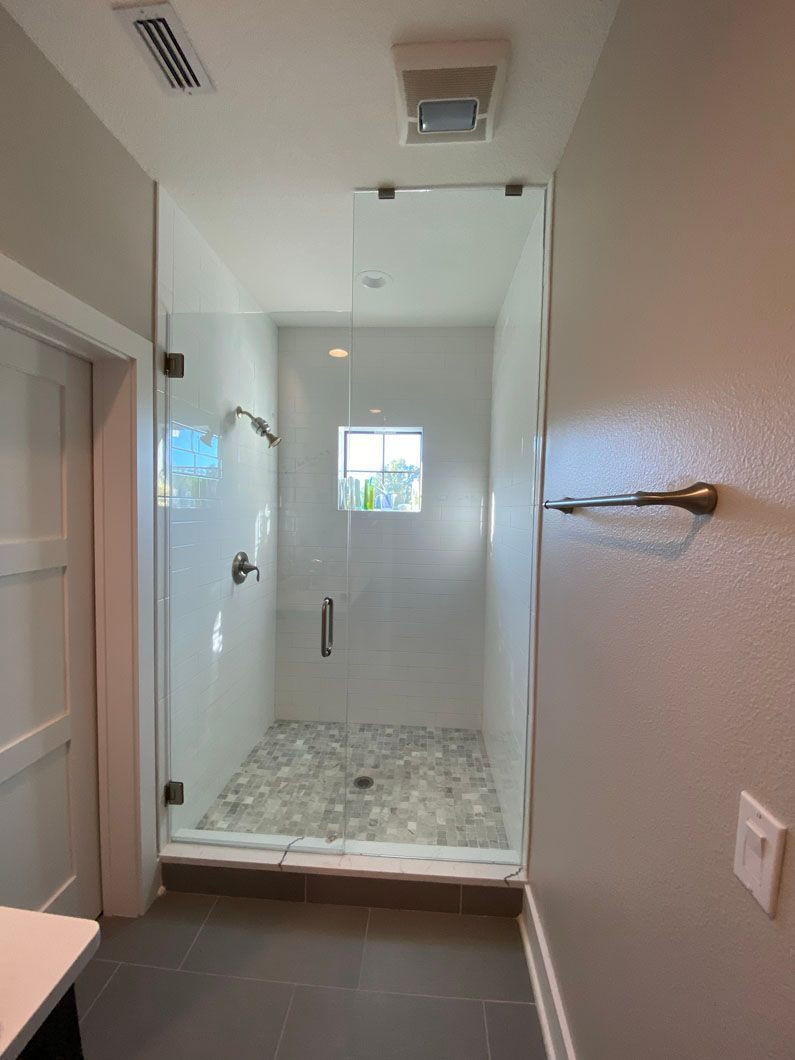 Shower with glass doors and tiled floor, in a modern bathroom.