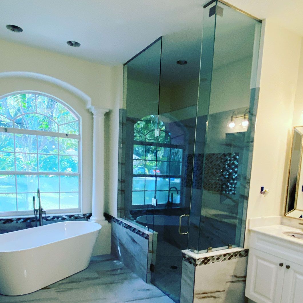 Modern bathroom with a glass shower enclosure, a bathtub near a window, and a vanity.