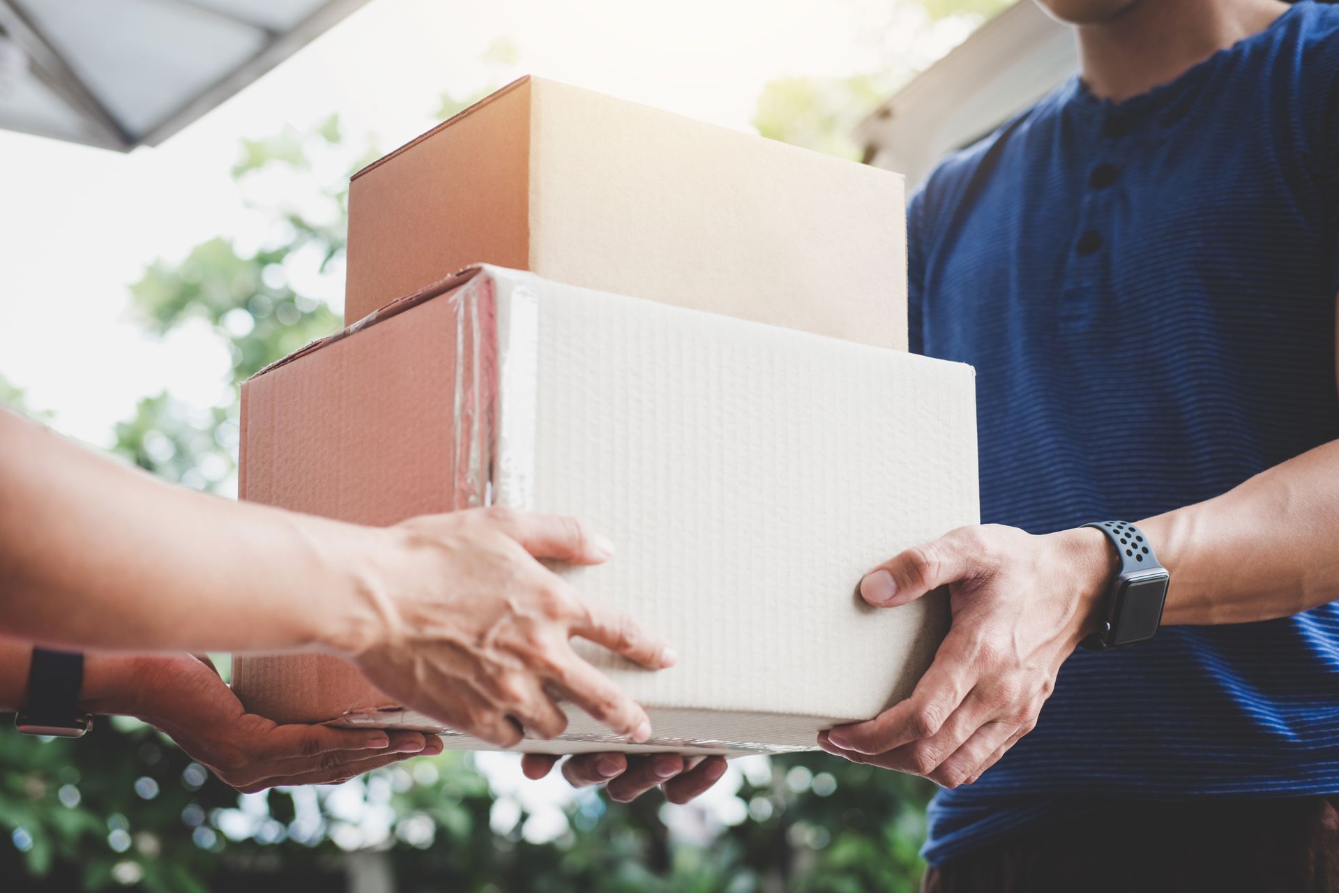 Package handoff during home delivery, with stacked boxes exchanged outdoors. Package handoff during home delivery, with stacked boxes exchanged outdoors.