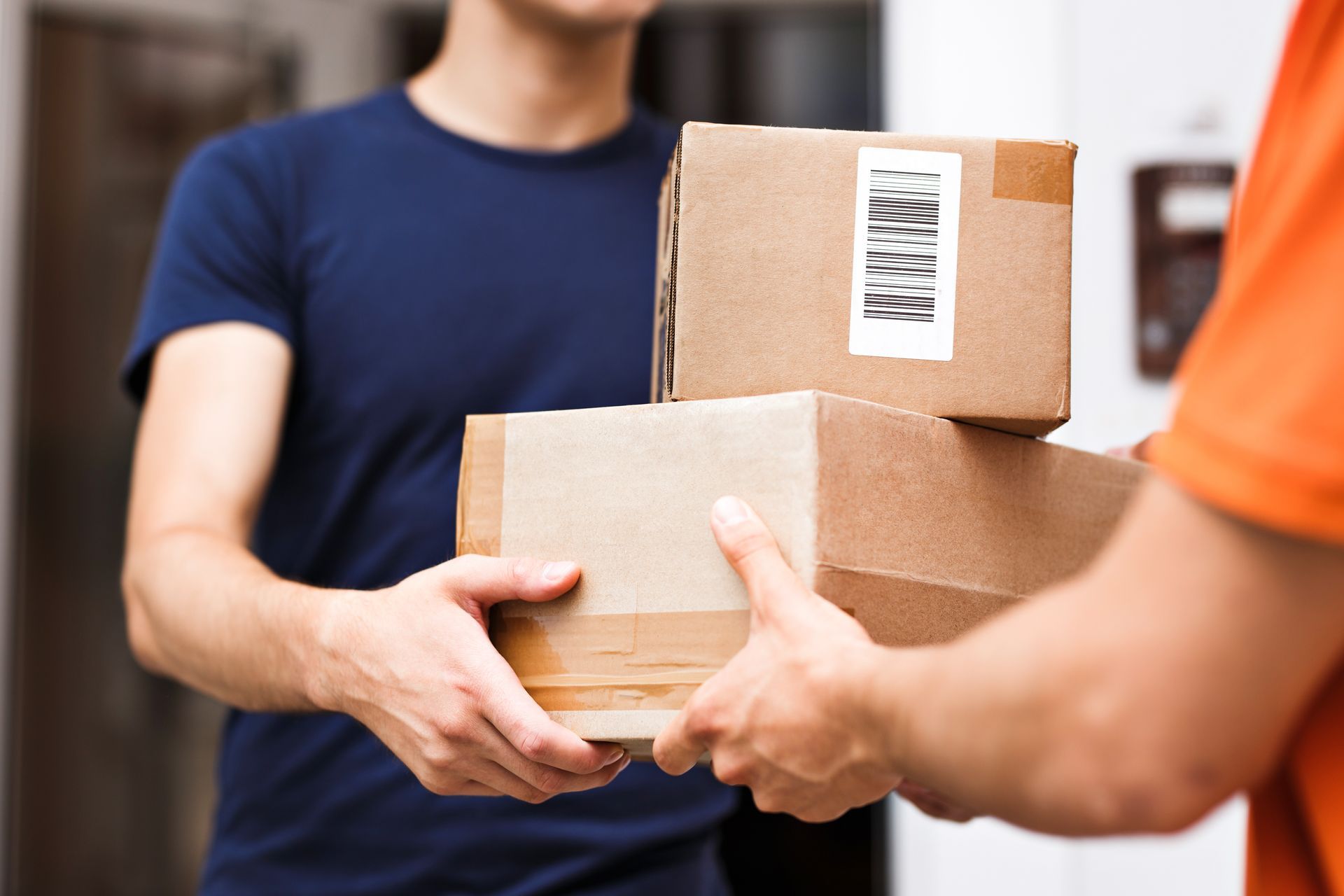 Delivery worker handing cardboard boxes to customer at doorway.