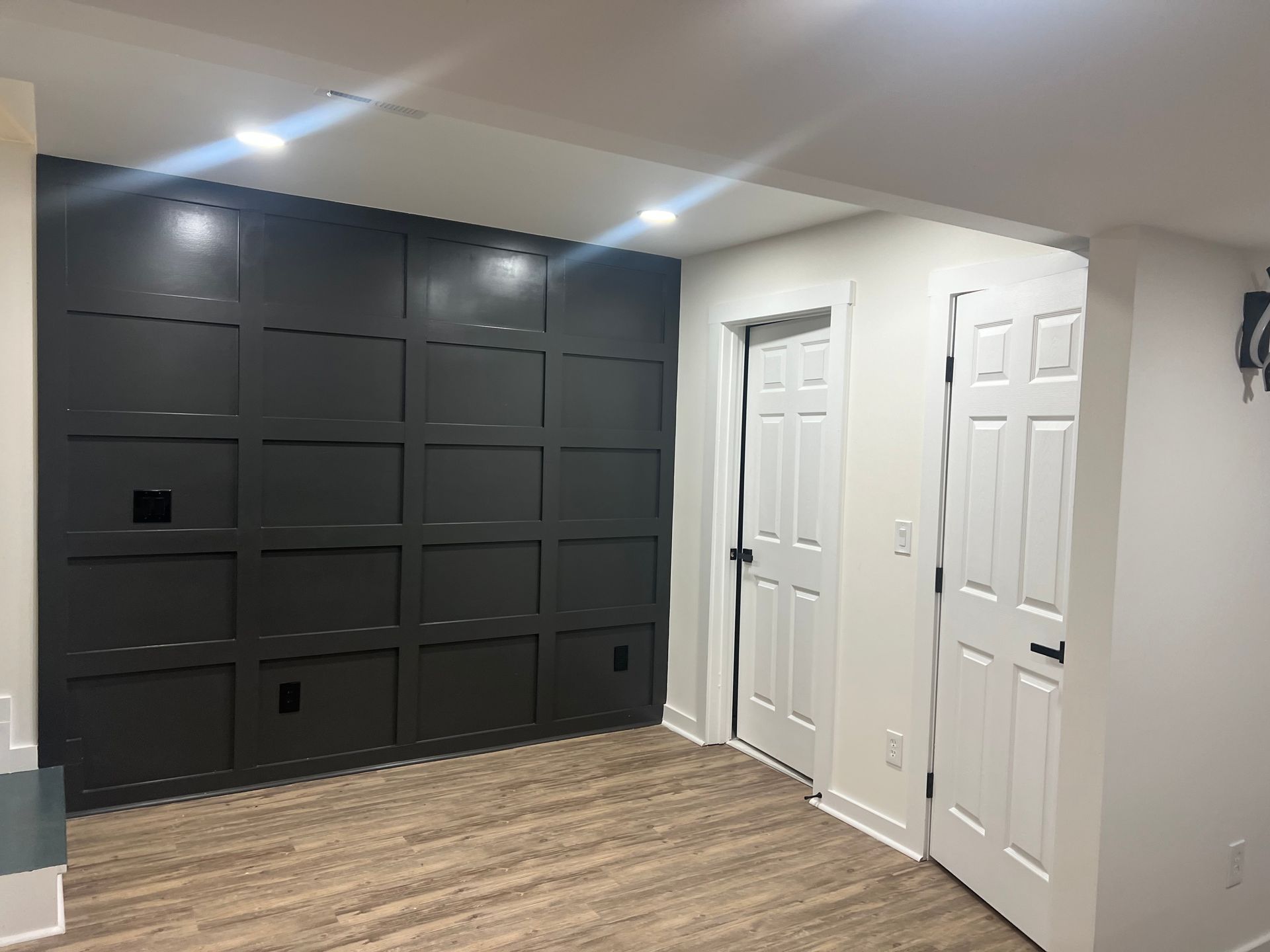 Finished basement with dark board and batten accent wall, recessed lighting, and luxury vinyl plank flooring in Woodstock Georgia