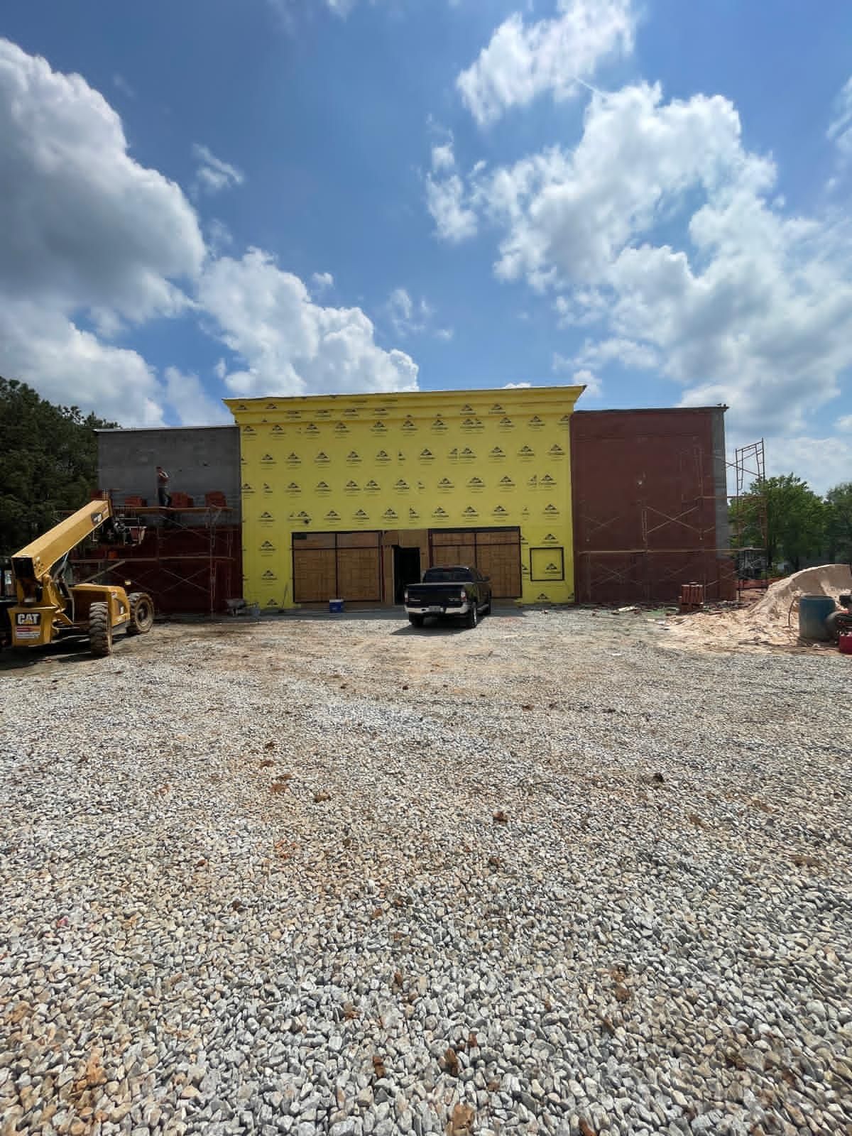 Commercial CMU block building with yellow moisture barrier wrap and CAT telehandler on active construction site in Marietta Georgia