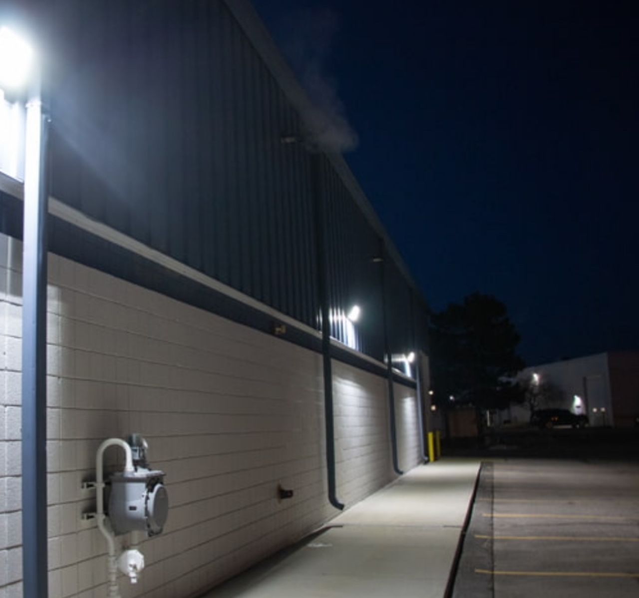 Commercial building exterior at night with LED wall-pack lighting, metal panel siding, and loading dock doors in Woodstock Georgia