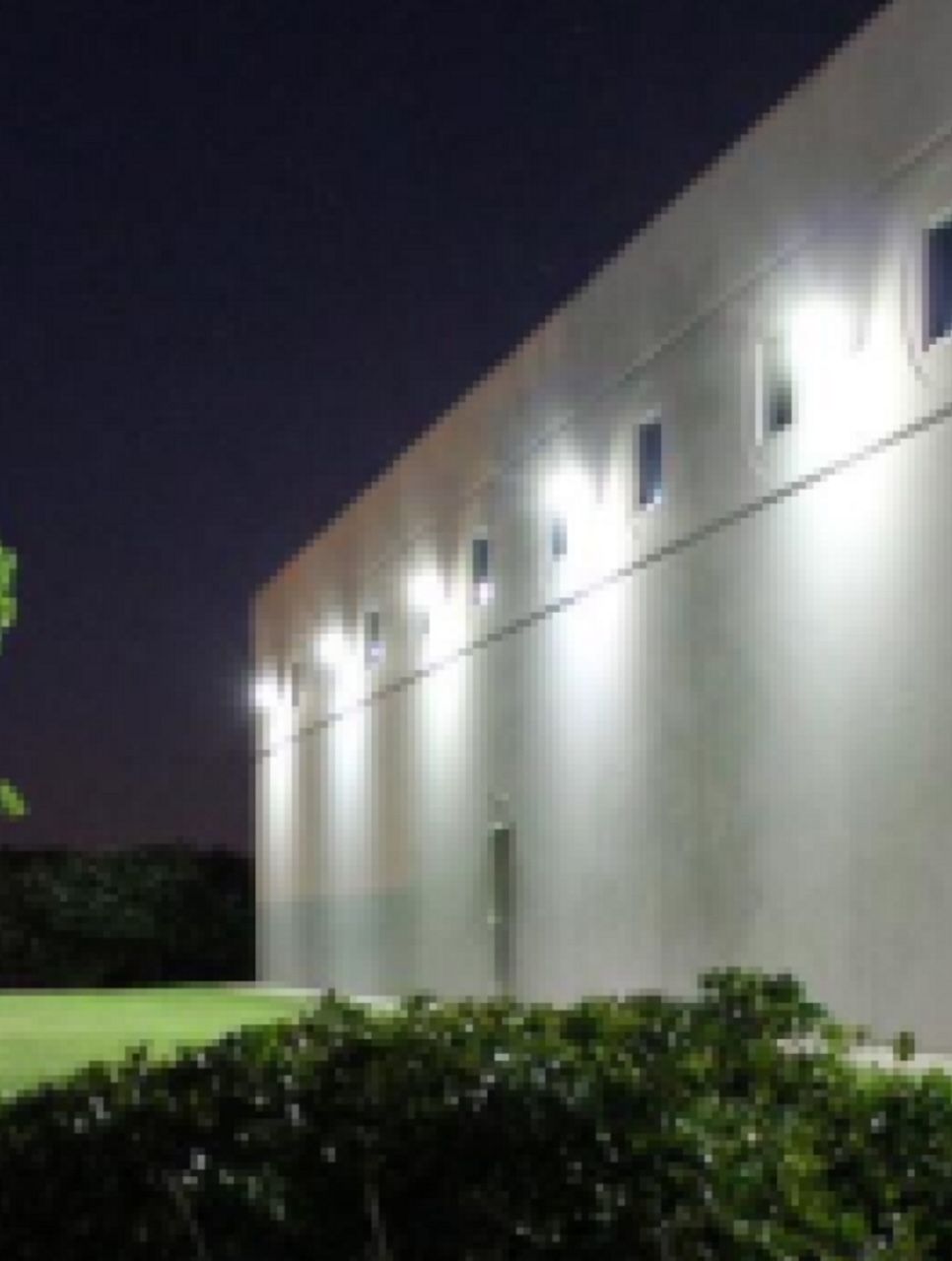 Commercial building exterior at night with wall sconce lighting and stucco finish in Roswell Georgia