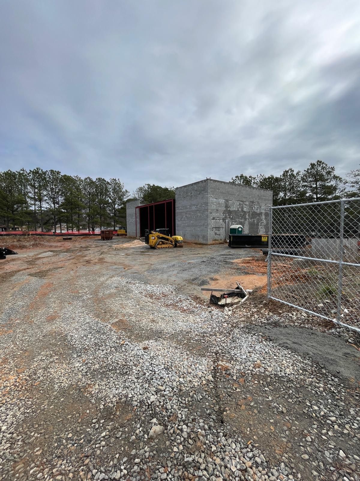 Early-phase commercial CMU block building shell with red iron framing and skid steer on active construction site in Roswell Georgia