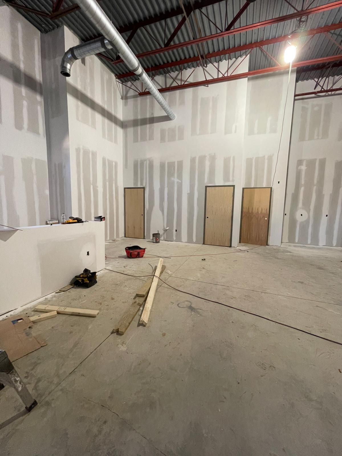 Commercial interior build-out with drywall walls, exposed HVAC ductwork, and red iron roof trusses in Marietta Georgia