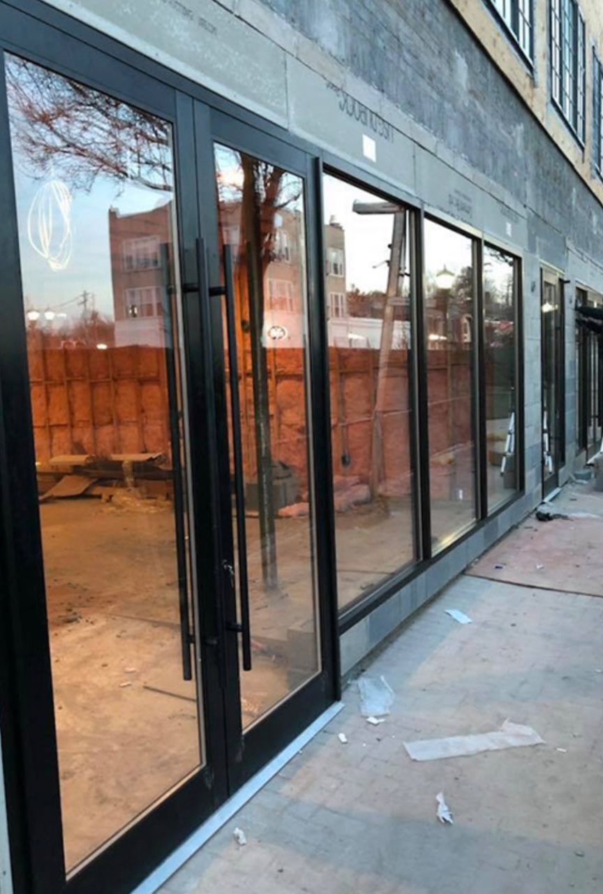 Commercial storefront glass curtain wall with matte black framing and entry door during tenant build-out in Roswell Georgia
