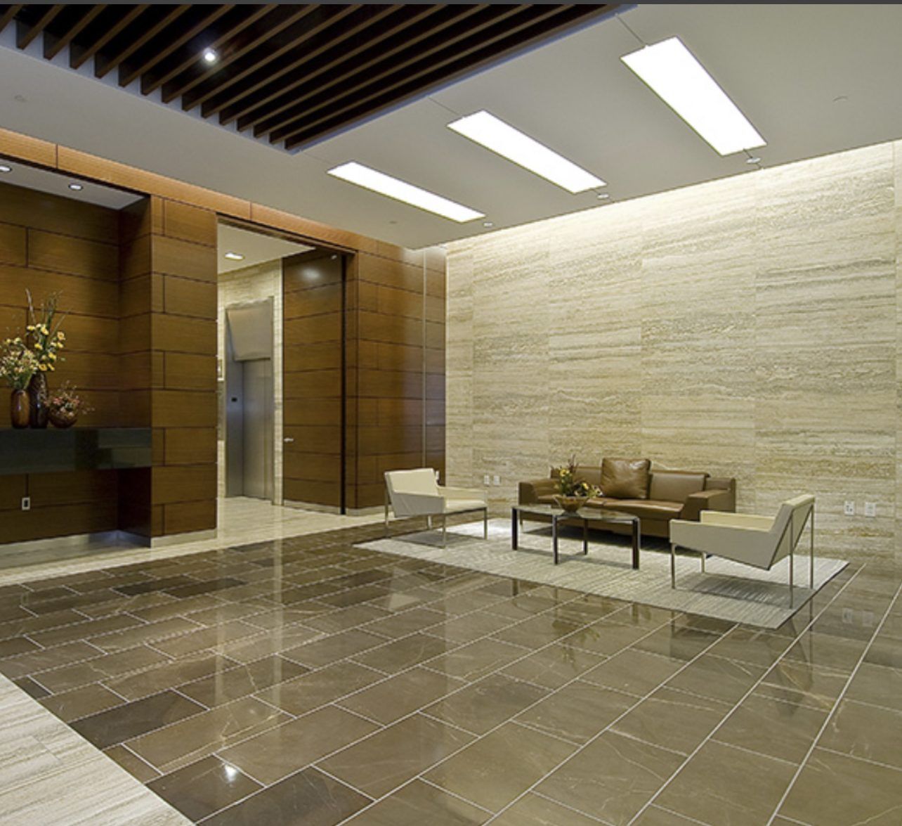 Renovated hotel lobby with travertine tile flooring and wood paneling completed by Art Design and Co