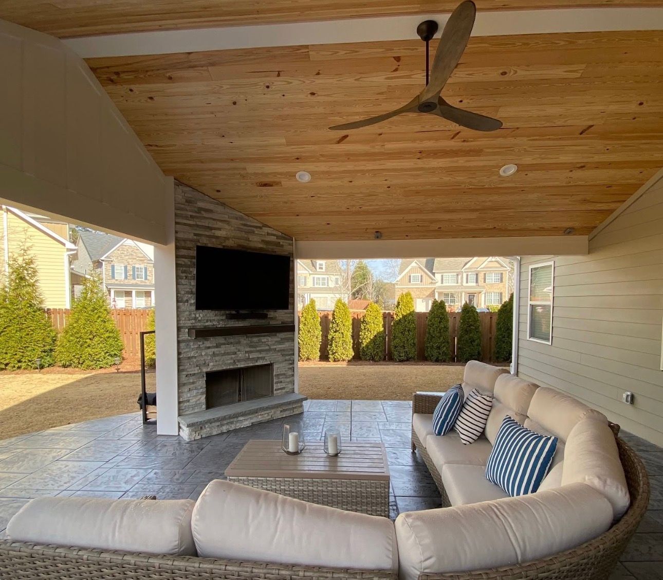 Luxury covered patio with cedar ceiling, stacked stone outdoor fireplace, TV mount, and stamped concrete in Woodstock Georgia