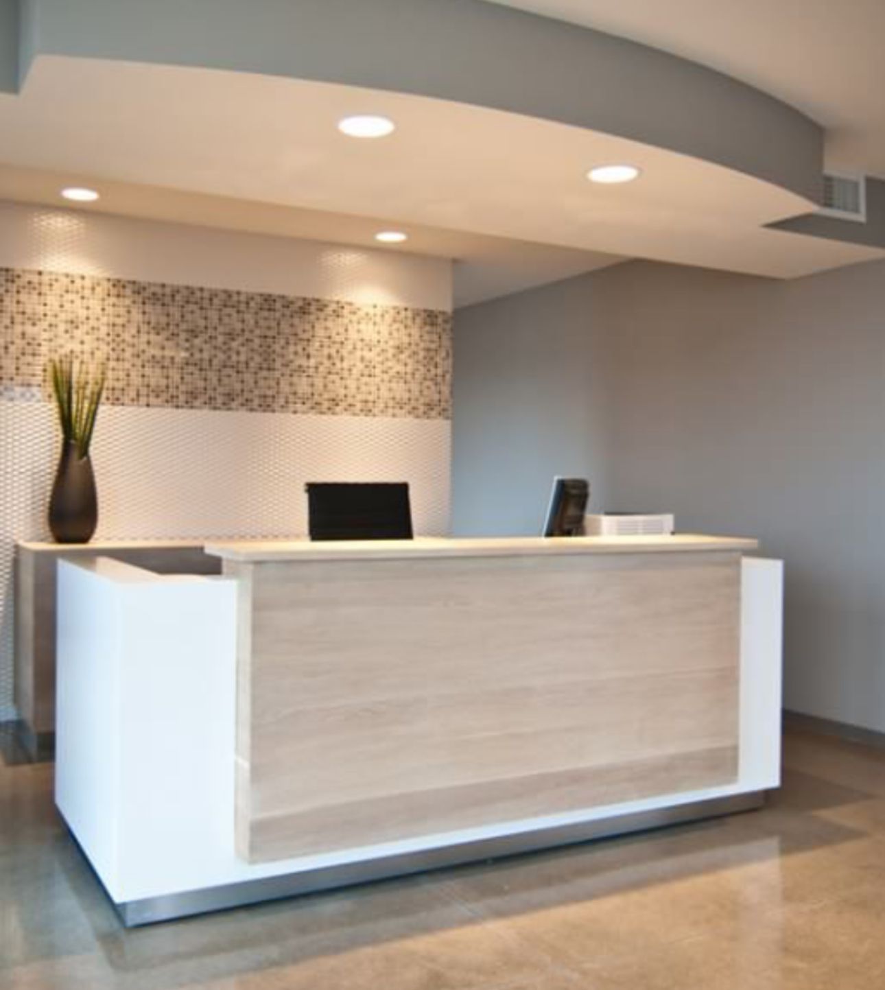Modern office reception area buildout with white reception desk mosaic tile accent wall and custom curved ceiling by commercial contractor serving Woodstock GA