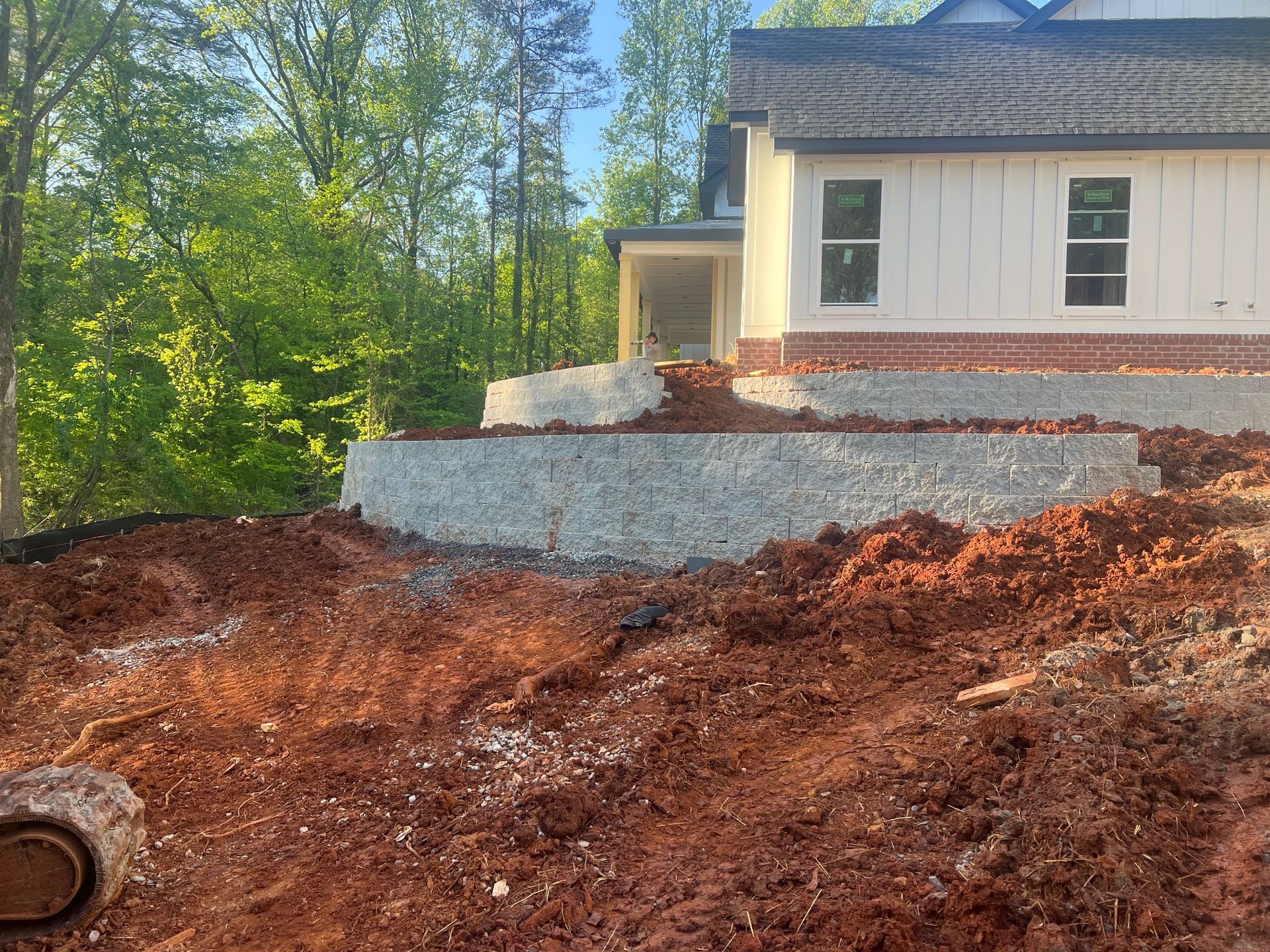 New home construction with block retaining wall installation and grading on Georgia red clay lot by residential construction contractor serving Woodstock GA
