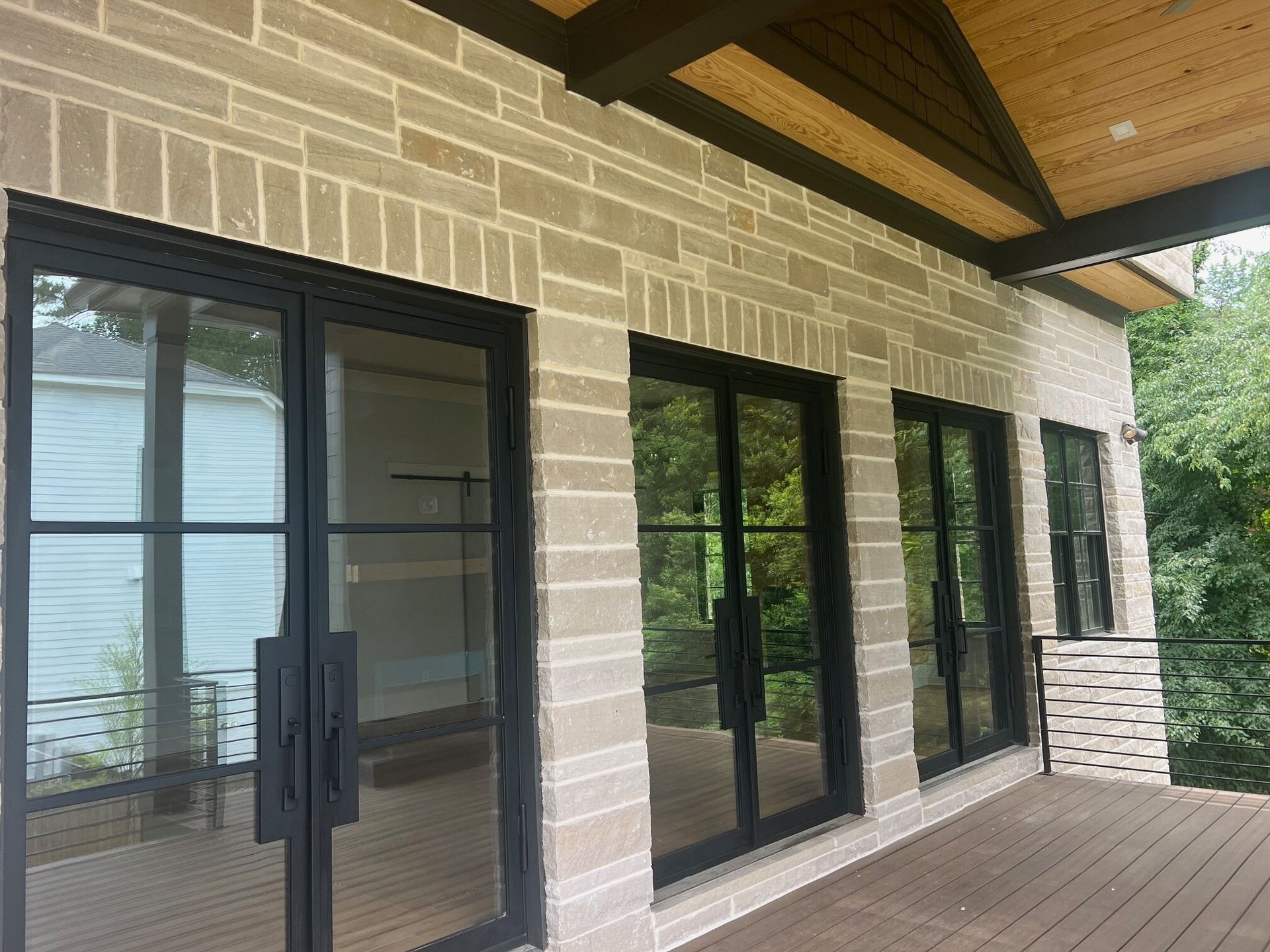 Covered porch with black-framed glass doors and stone exterior finish in Woodstock, Georgia