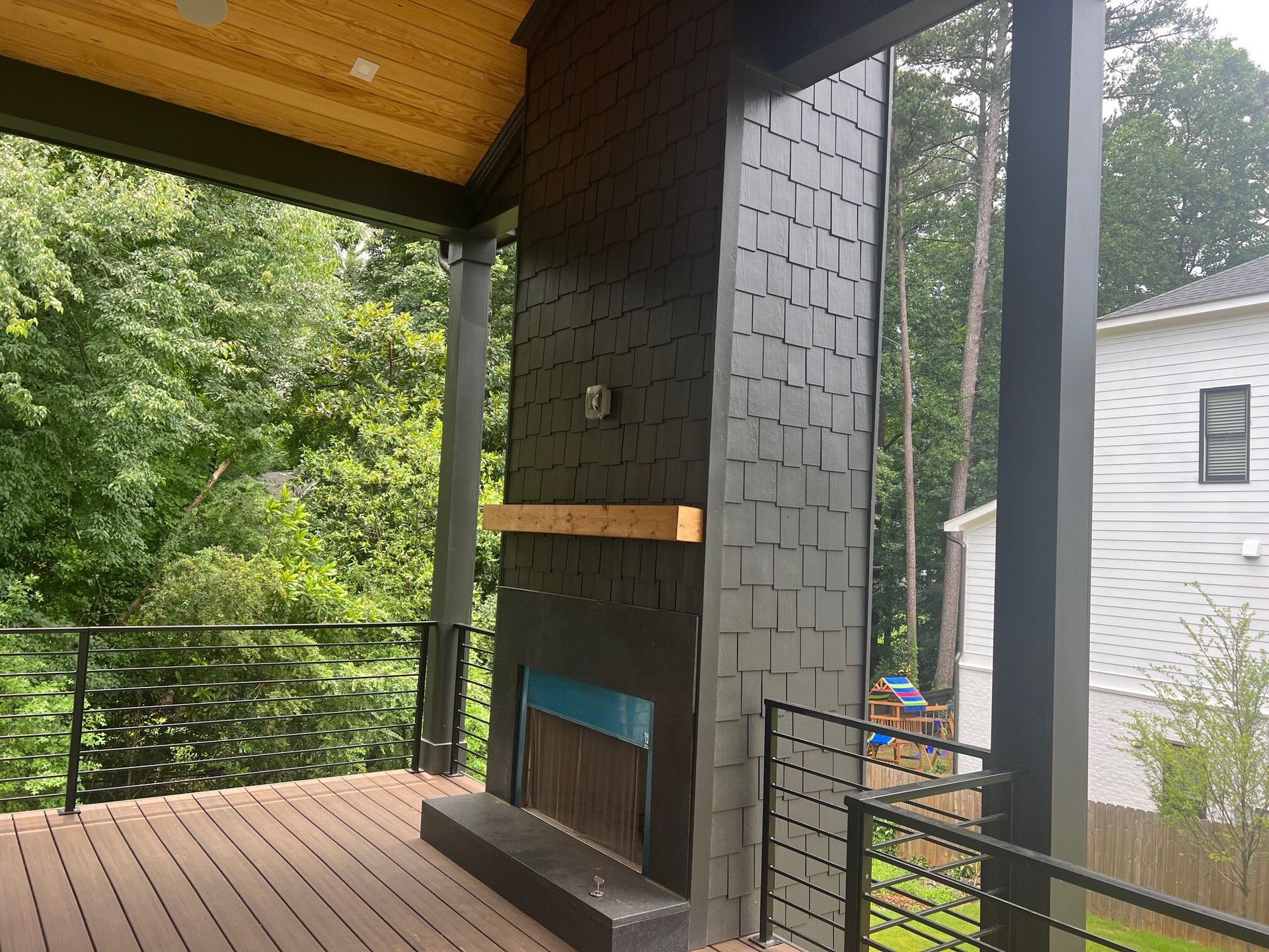 Covered open-air porch with outdoor fireplace and cable railing in Atlanta, Georgia