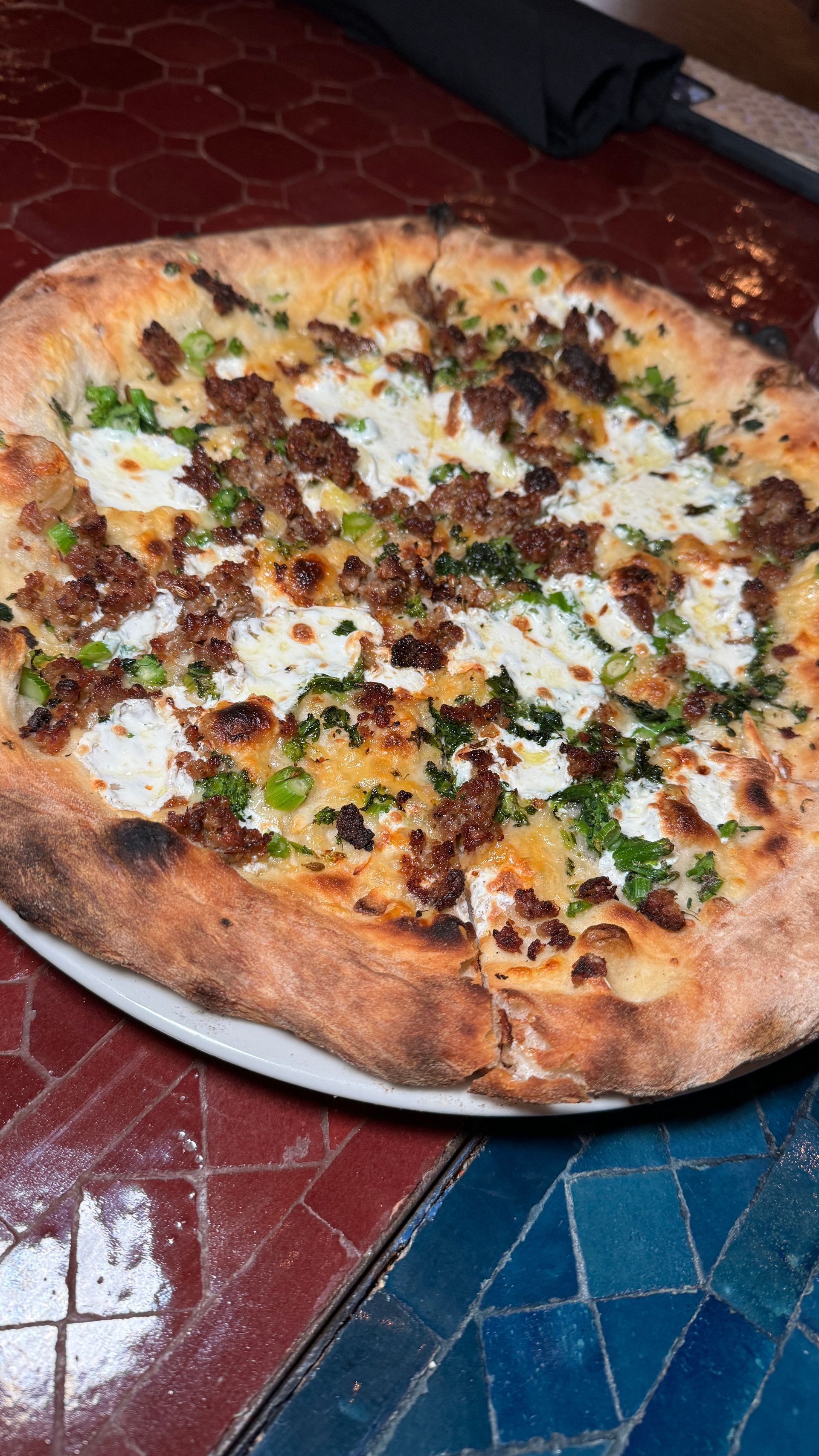 A pizza is sitting on a white plate on a table.