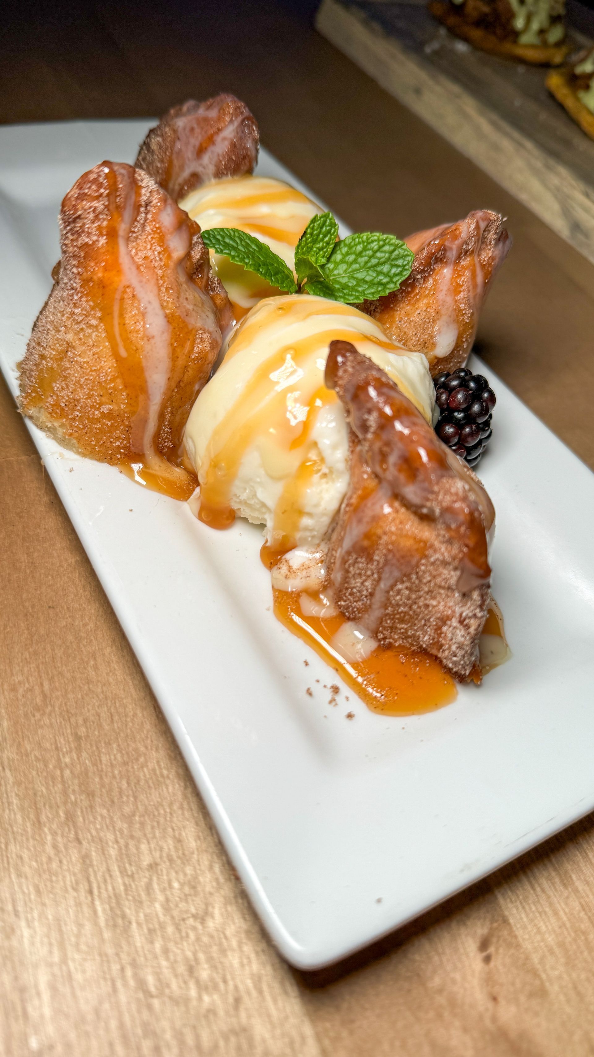 A white plate topped with a dessert and ice cream on a wooden table.