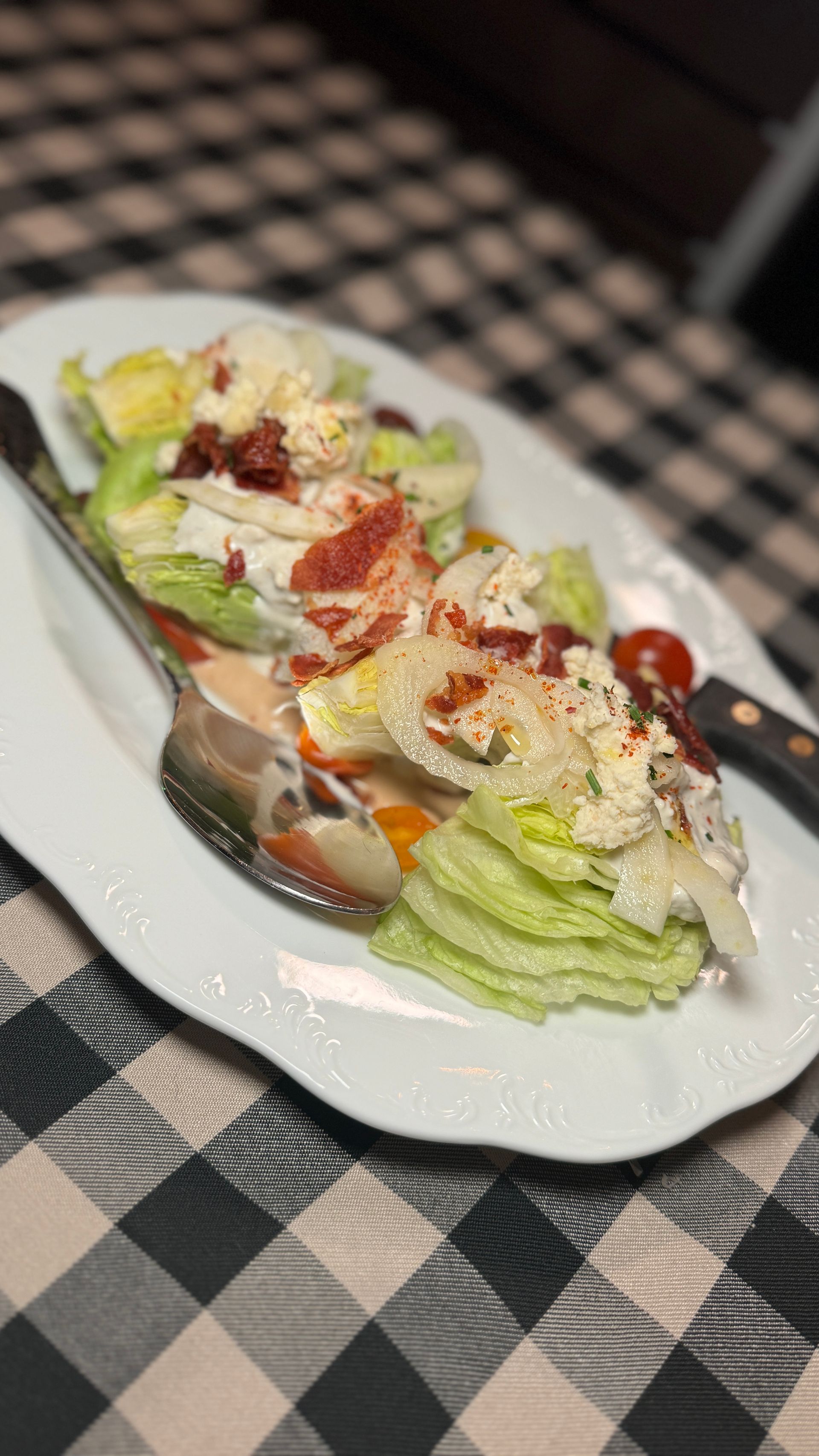 A white plate topped with a salad and a spoon on a table.