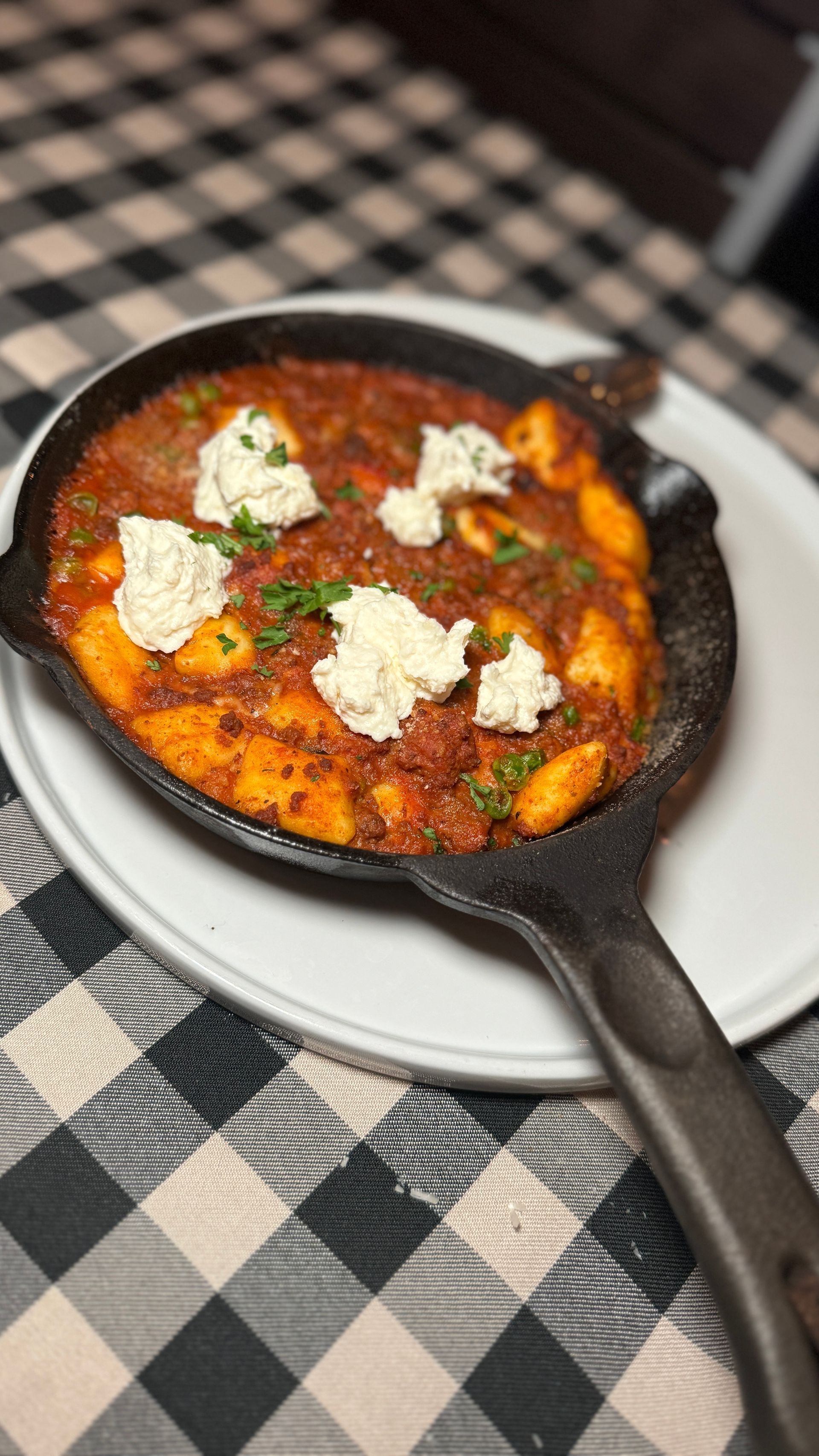 A skillet filled with food is on a plate on a table.
