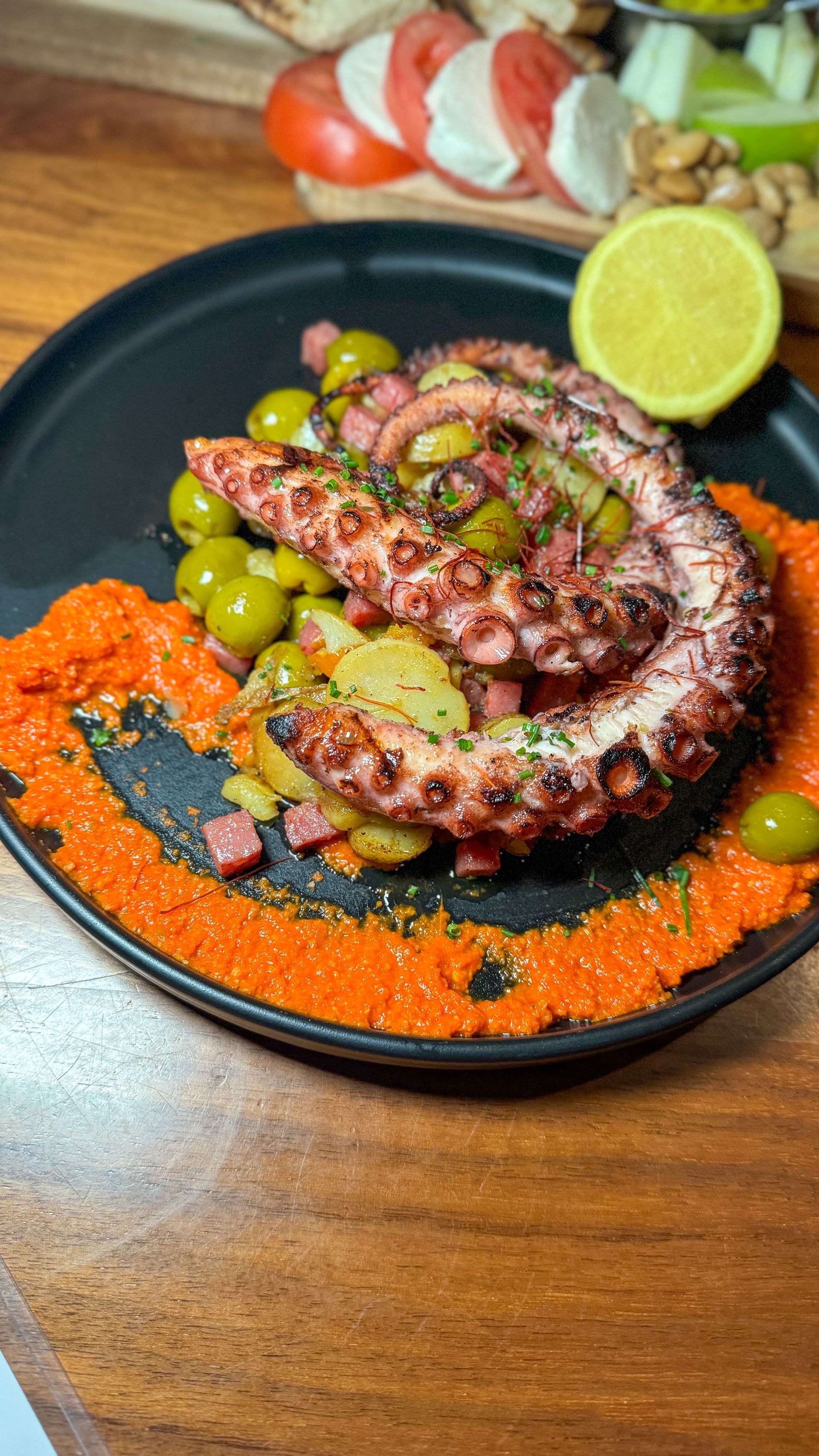 A close up of a plate of food with an octopus on a wooden table.