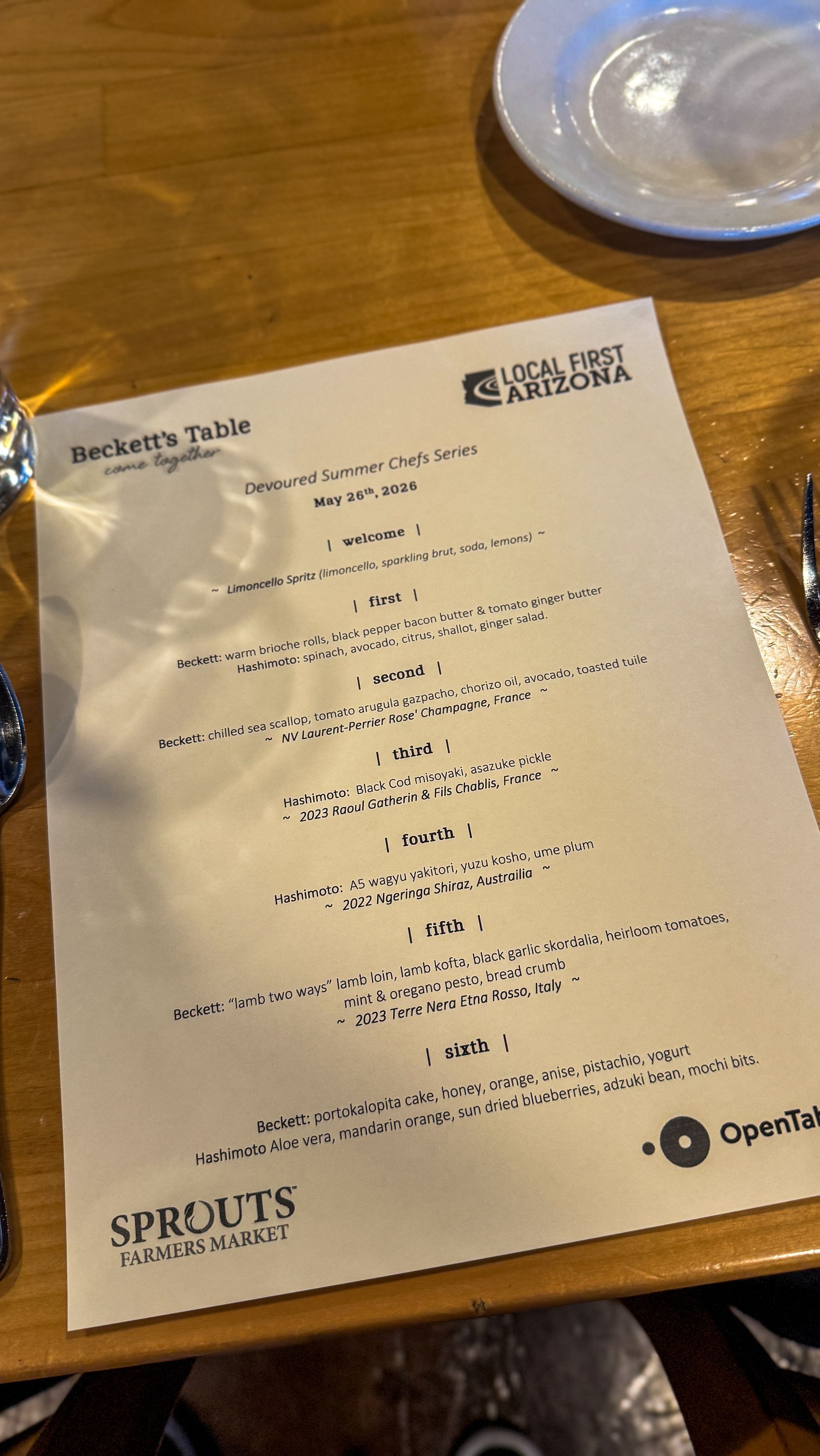Printed receipt on a wooden restaurant table with a plate nearby.