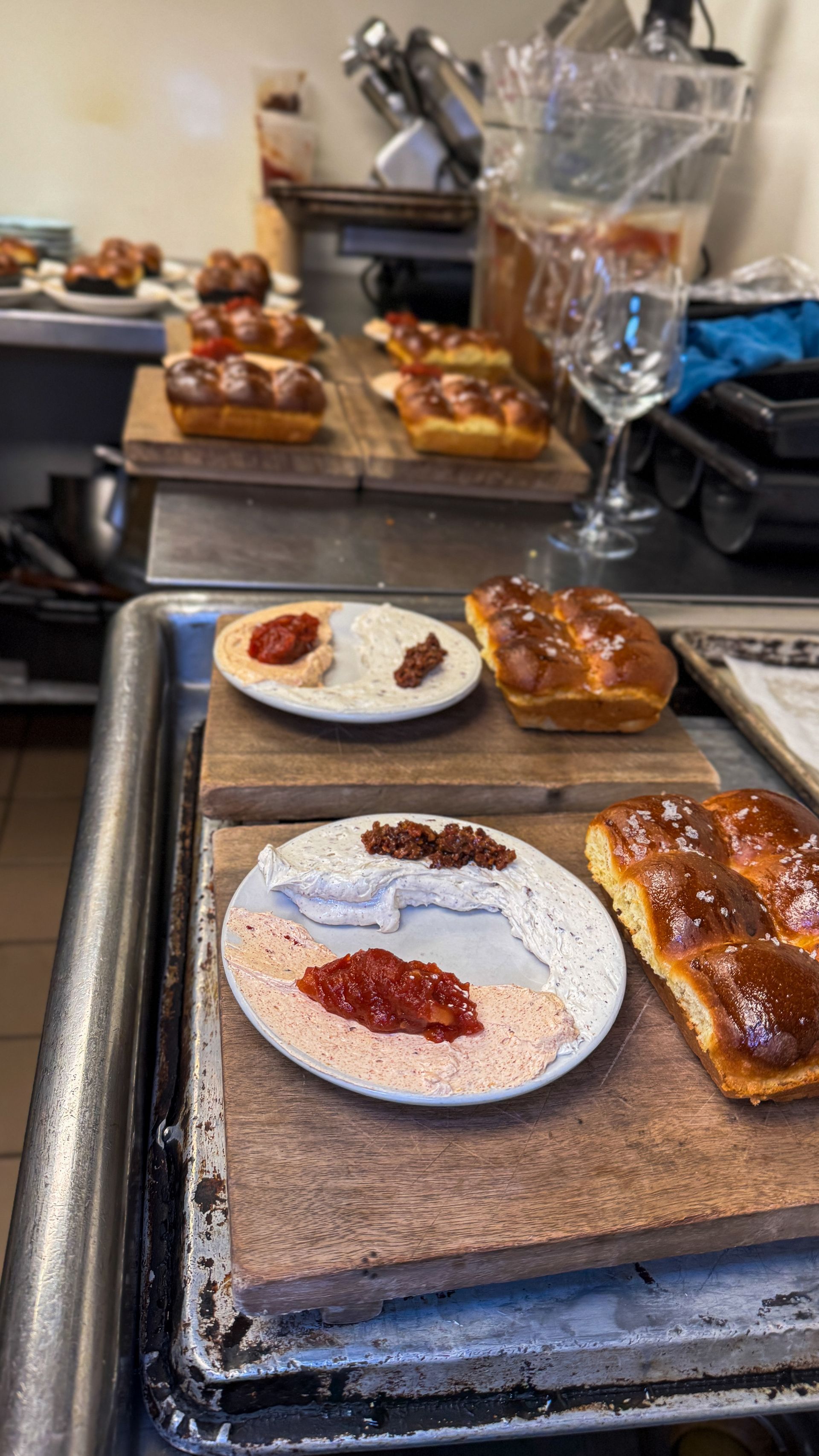 Plated pastries on a tray at a cafe counter, with a glass and tongs in the background