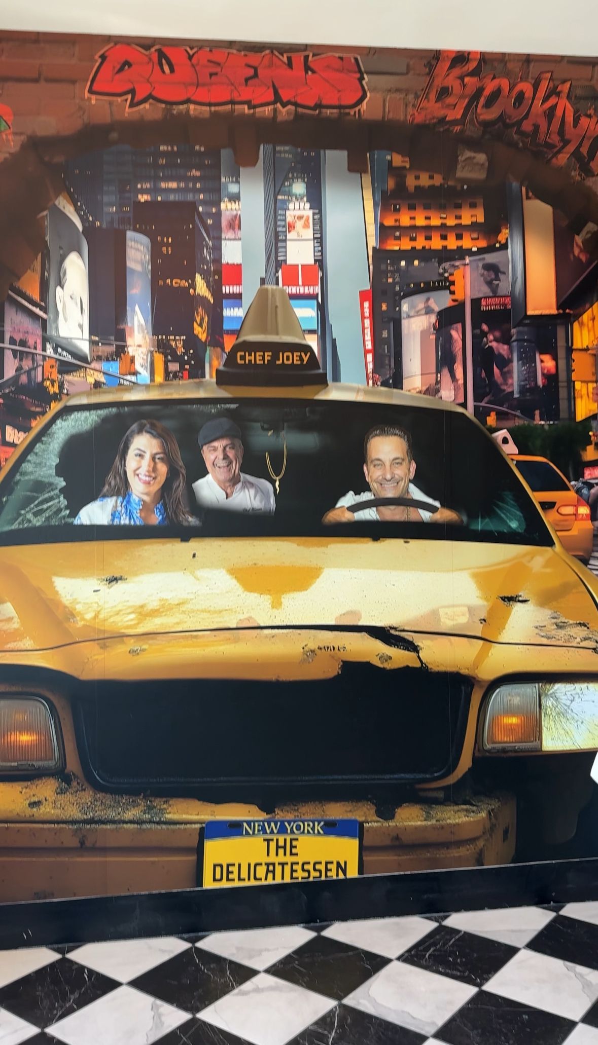 Family in a yellow New York City taxi; Times Square backdrop, smiling, city lights.