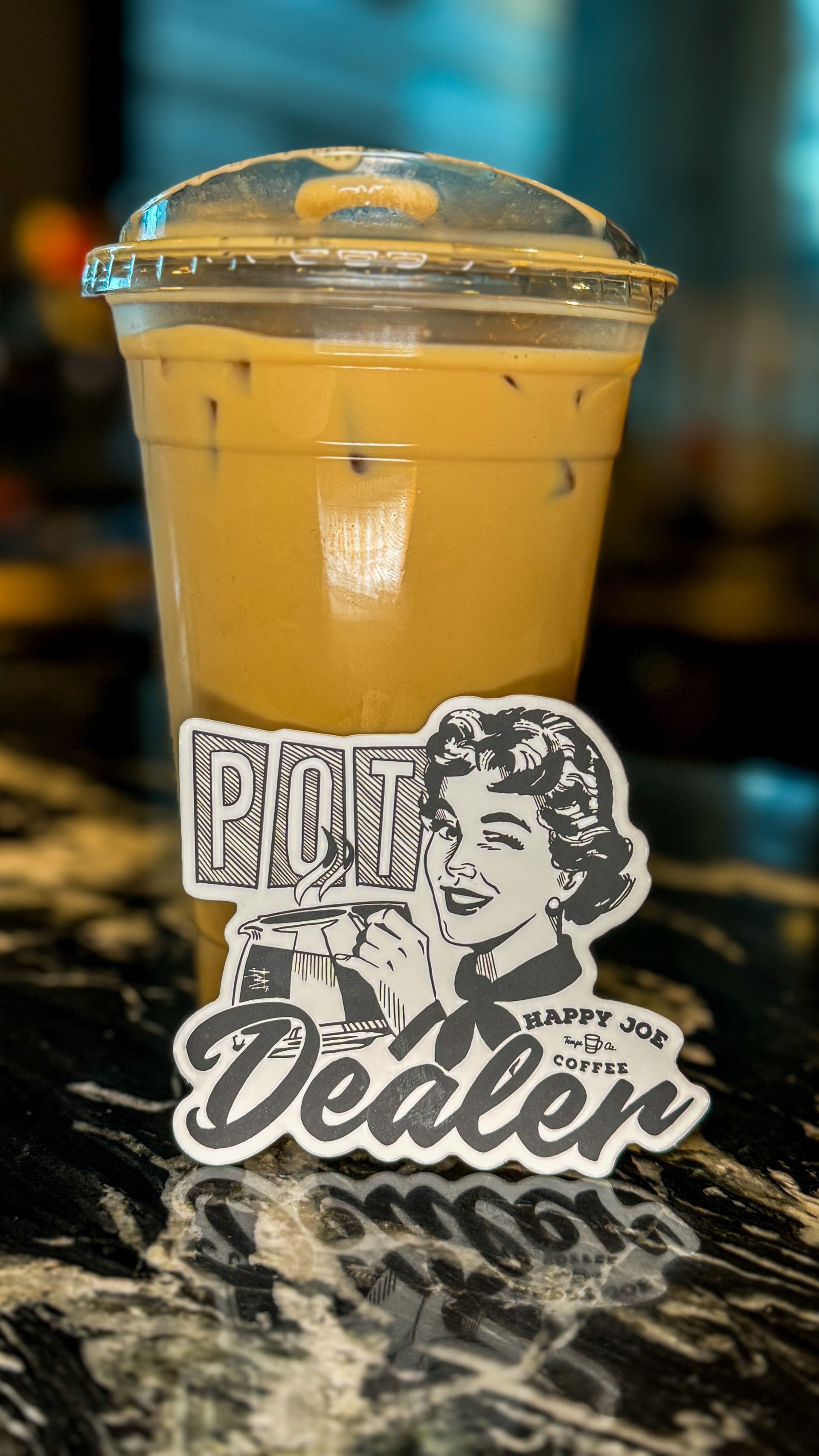 Iced coffee in a clear plastic cup with a lid, sitting on a counter next to a 