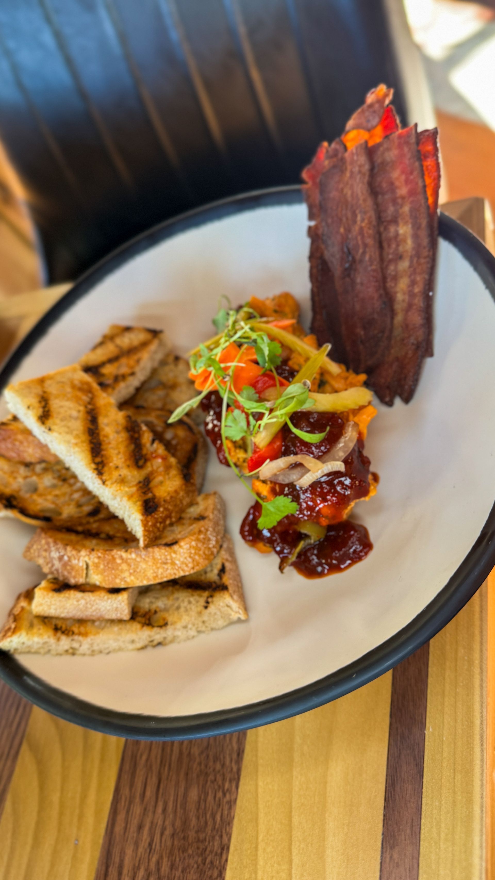 Plated gourmet meal with grilled meat, slaw, and toasted bread on a white plate