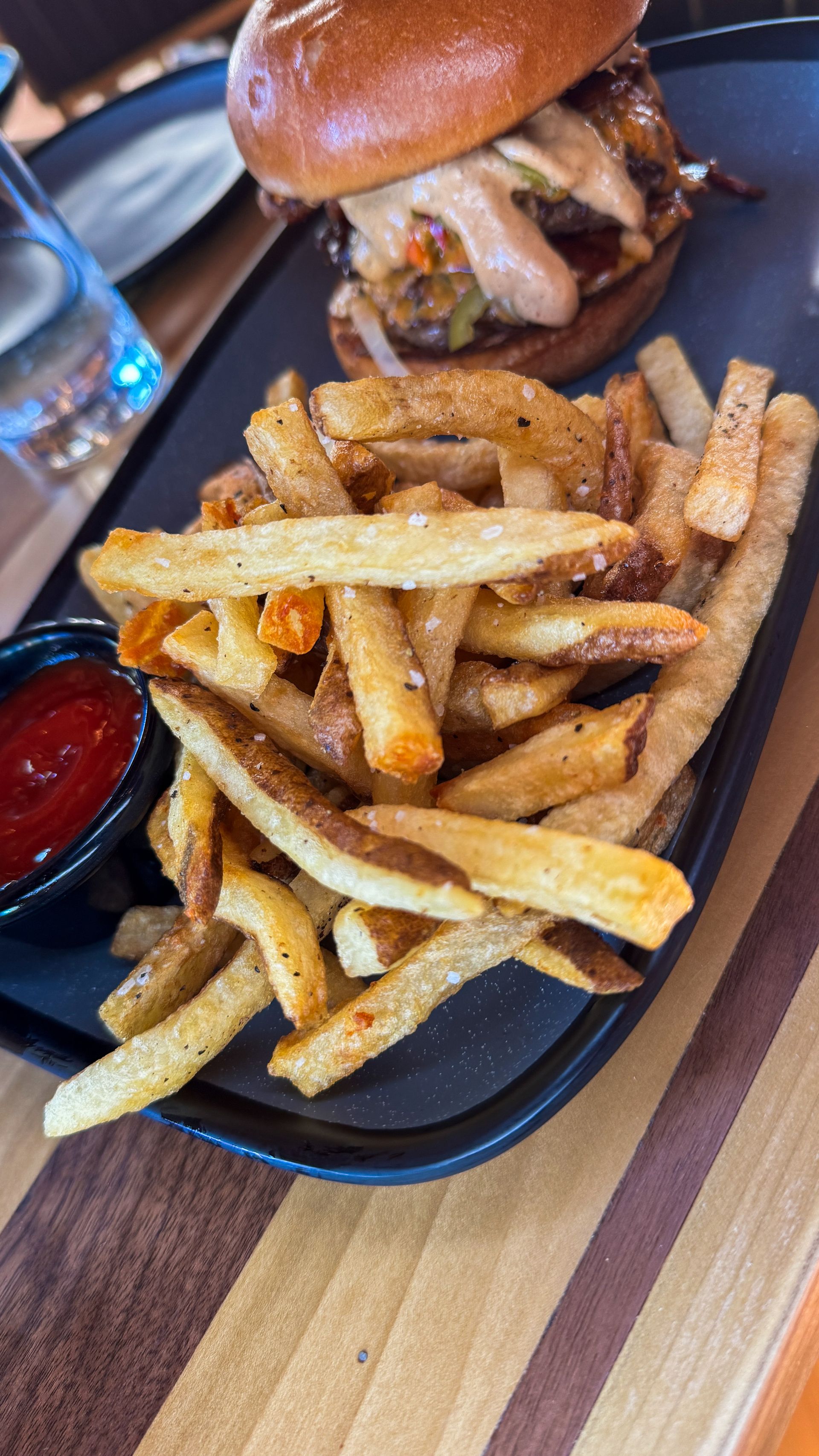 Burger and fries on a black tray at a restaurant table