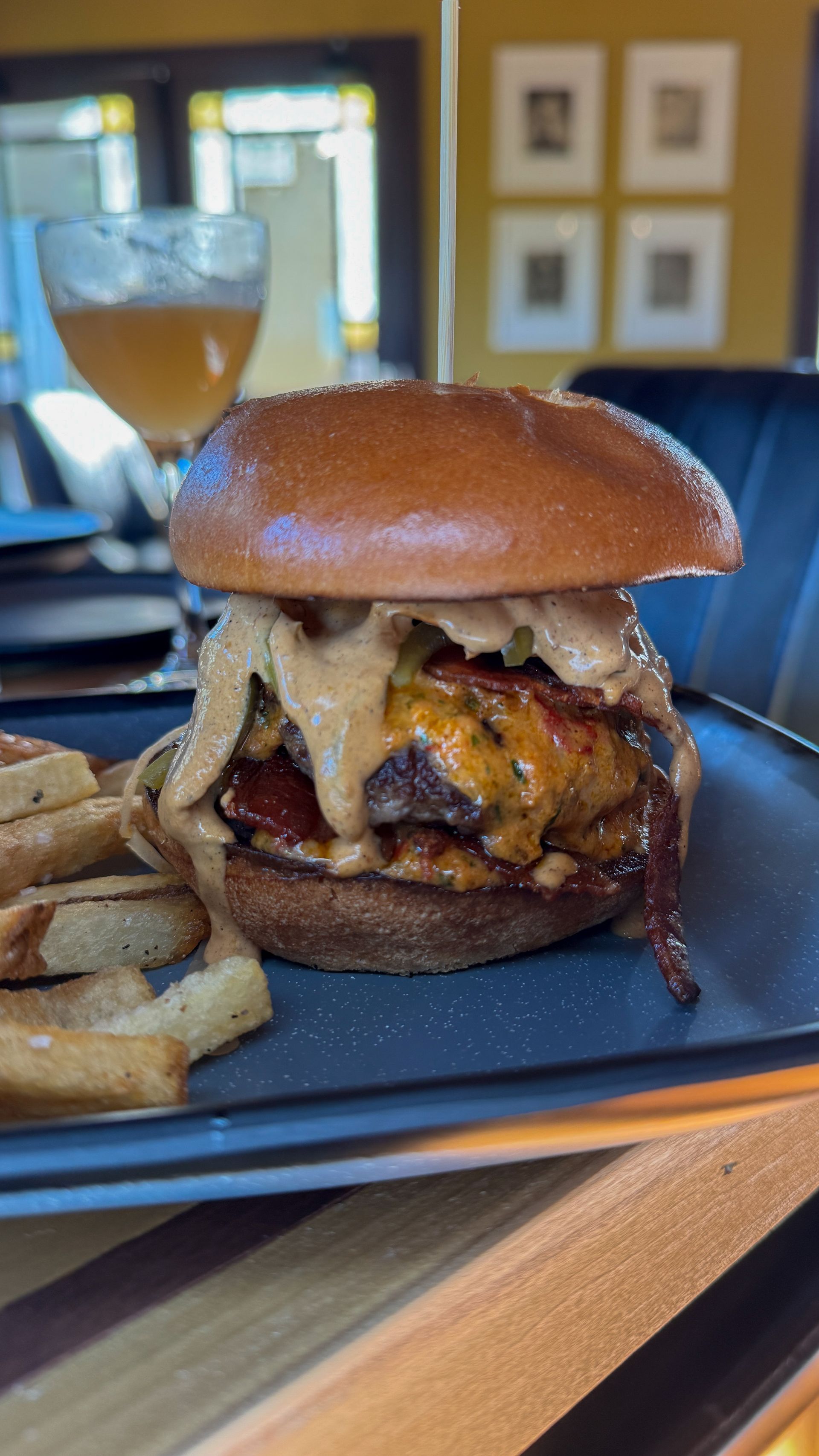 Cheeseburger with fries on a plate beside a glass of white wine in a restaurant
