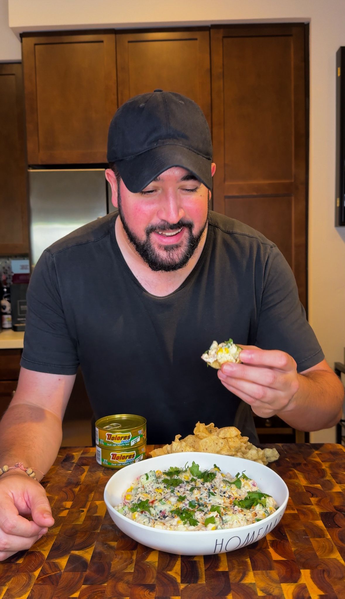 Man holding a tray of loaded nachos, brown cabinets in background, excited expression.