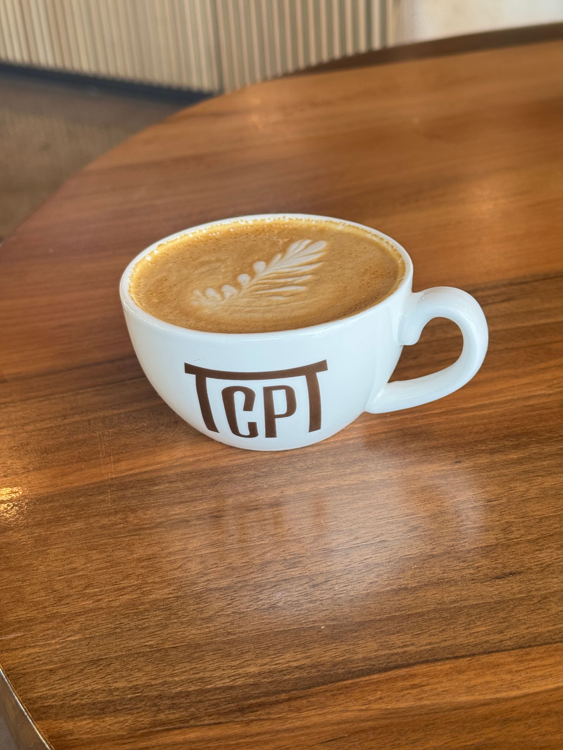Cup of coffee with latte art on a wooden table, featuring 