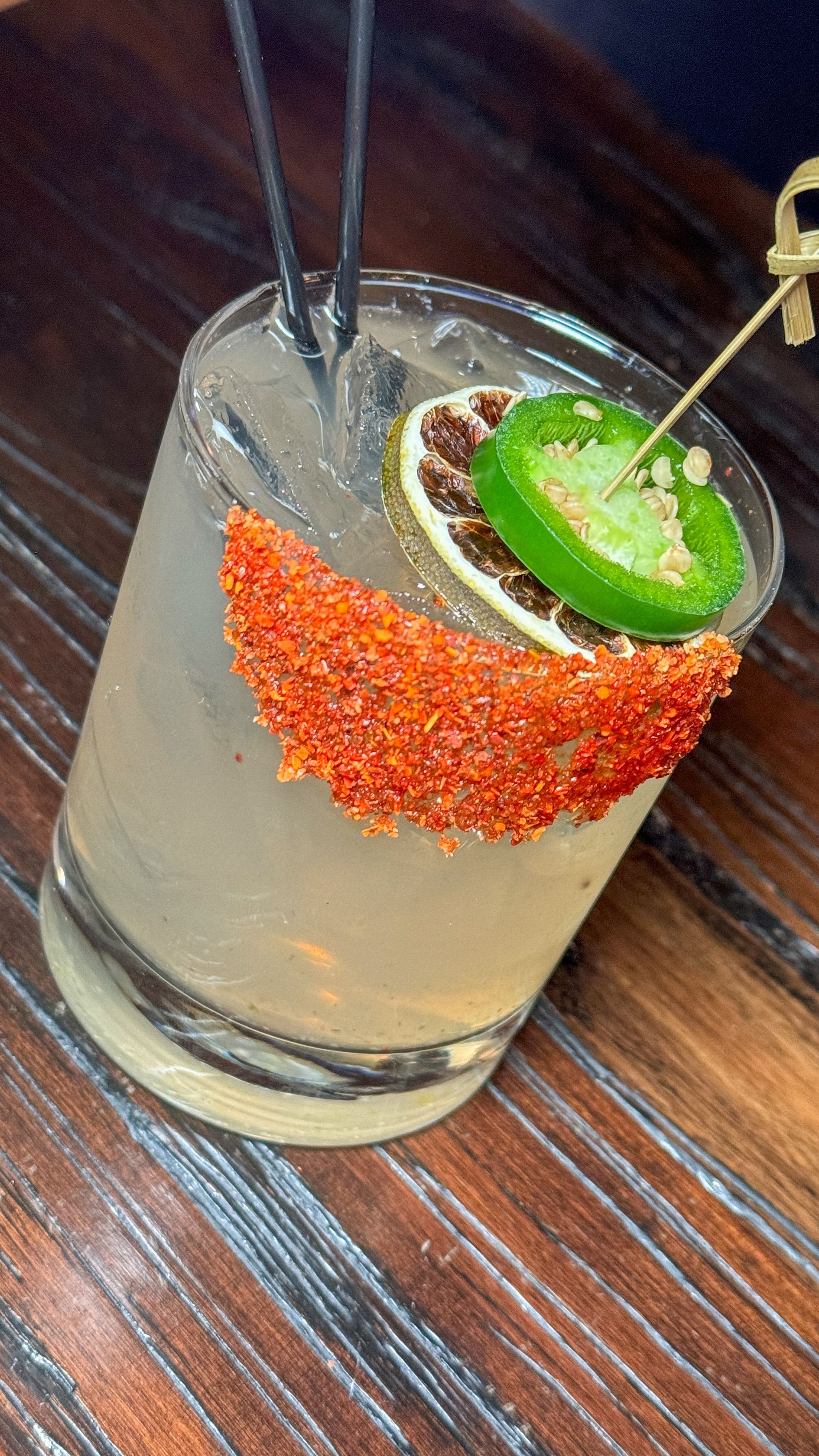 A close up of a drink in a glass on a wooden table.