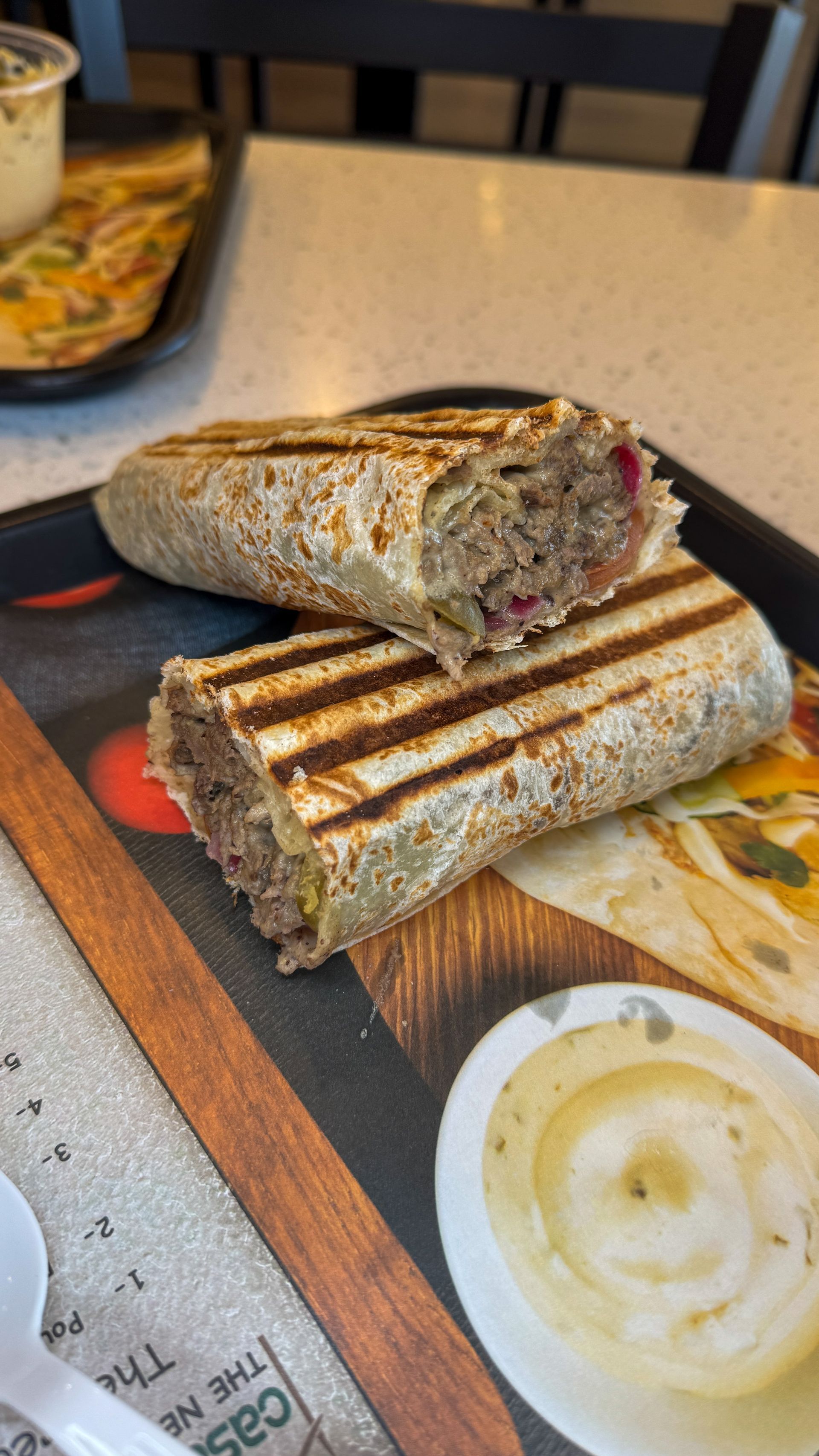 Grilled wrap sandwich, cut in half, on a tray.