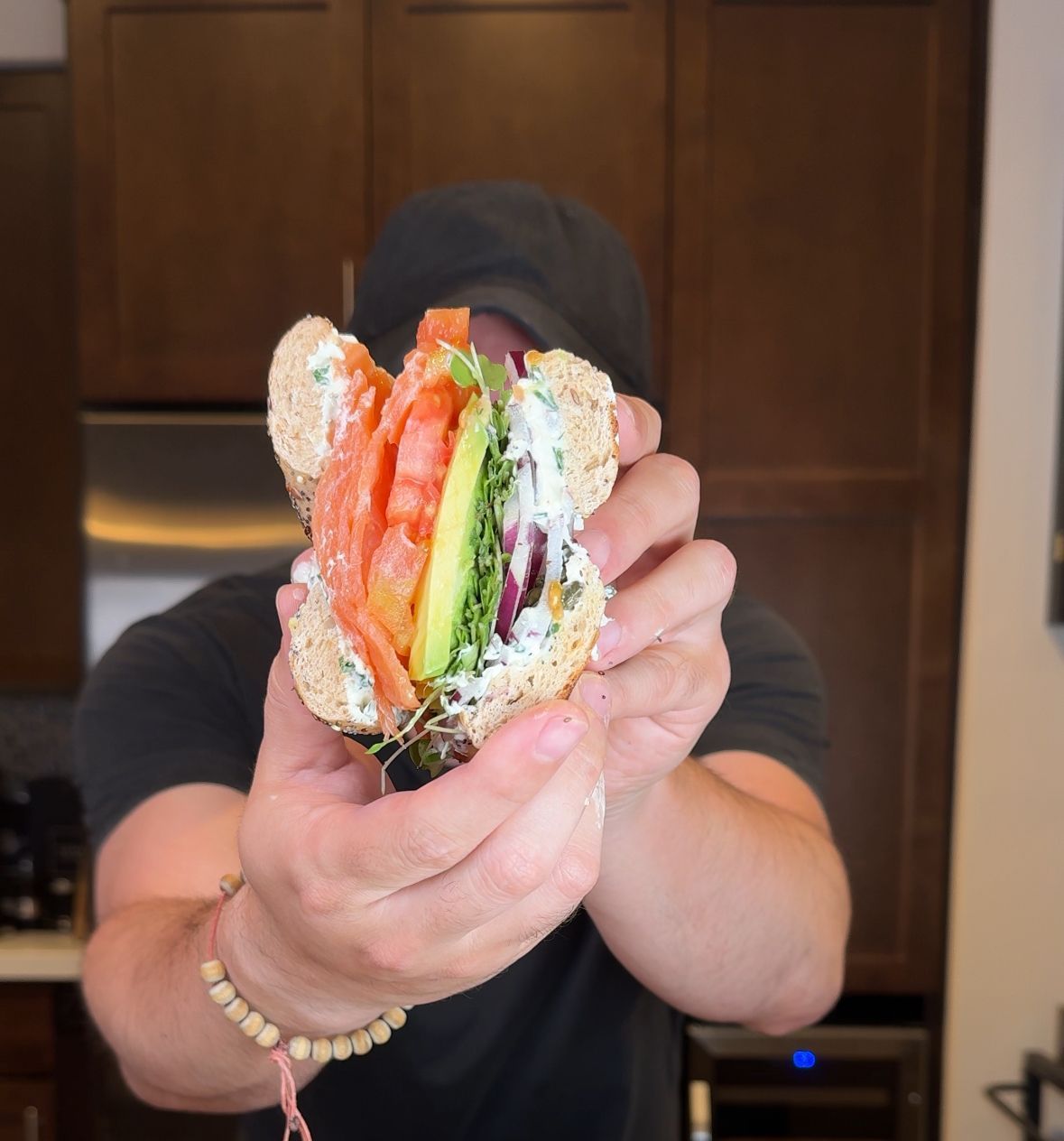 A man is holding a sandwich in front of his face