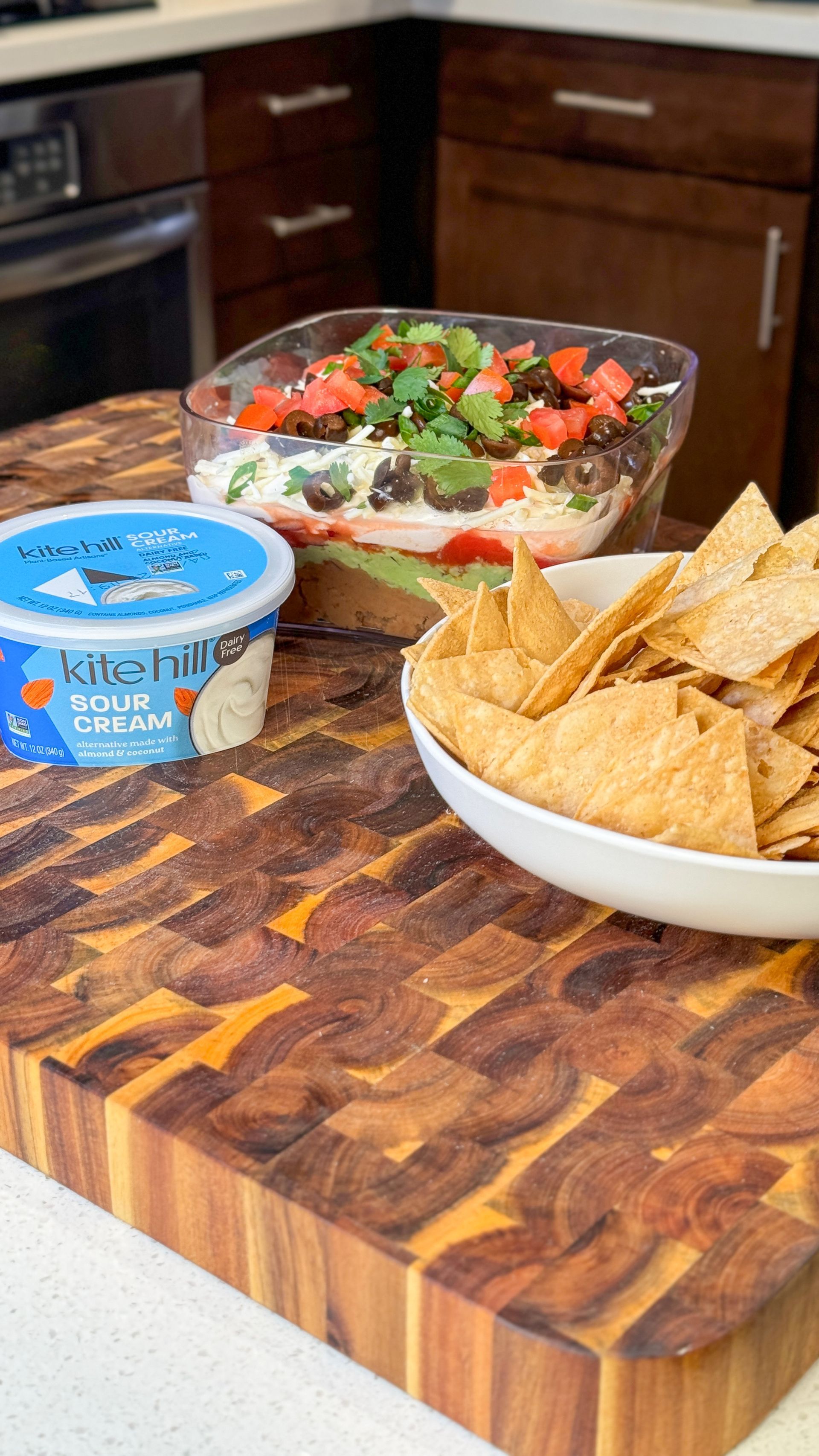 A bowl of salsa and tortilla chips on a wooden cutting board.