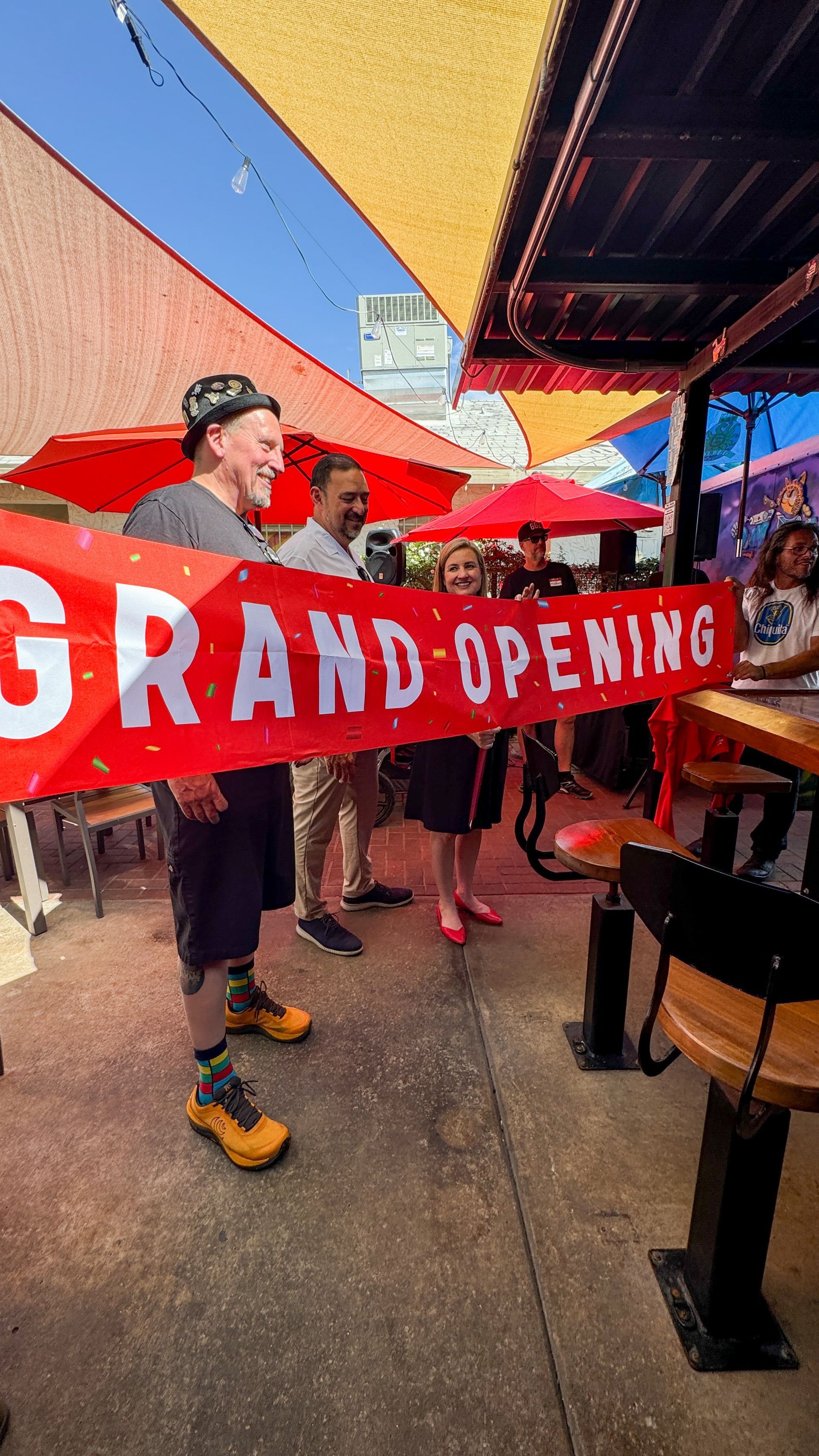 A man is holding a red banner that says `` grand opening ''.