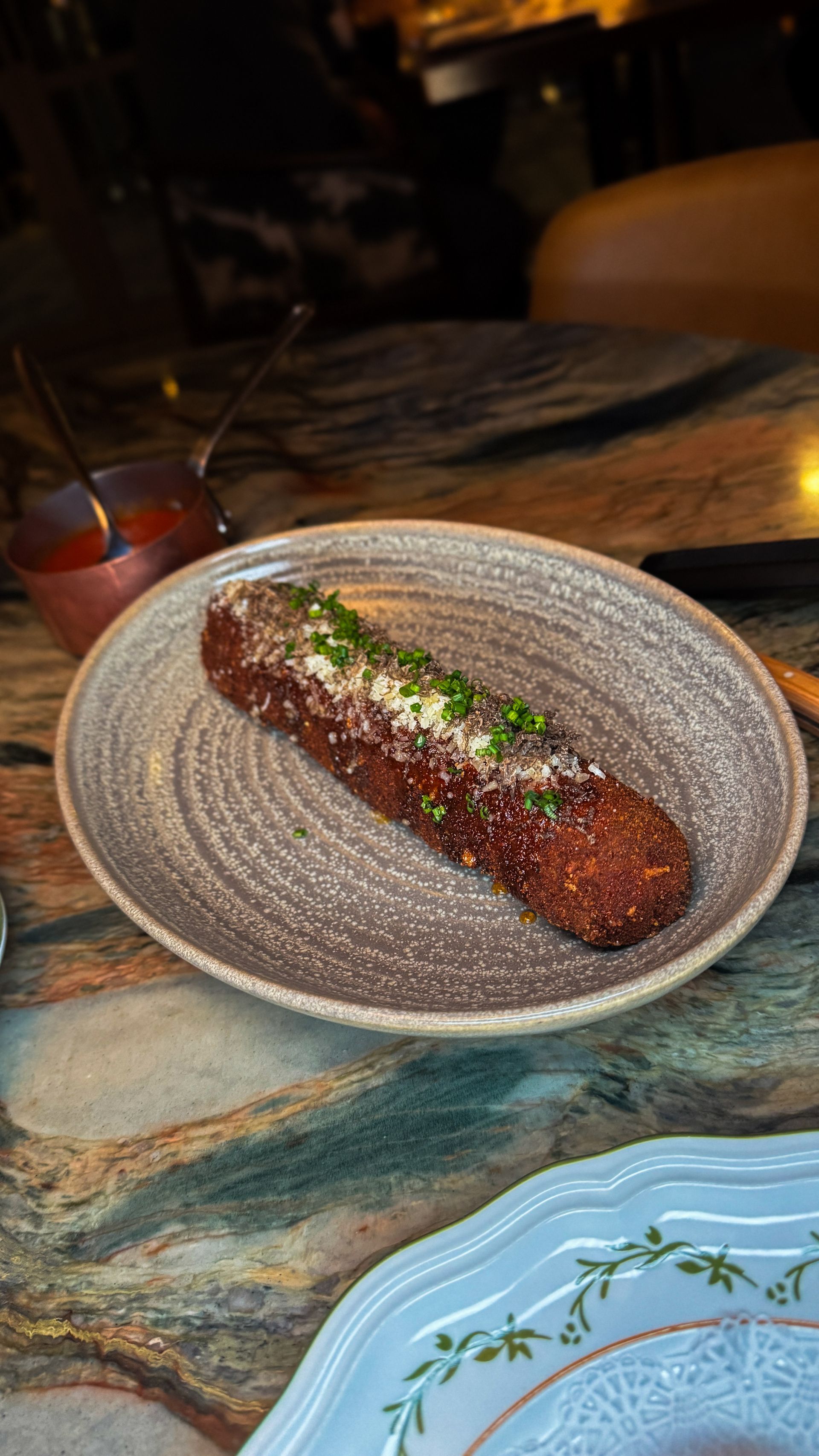 Long glazed dessert roll on a gray plate with powdered sugar, on a restaurant table