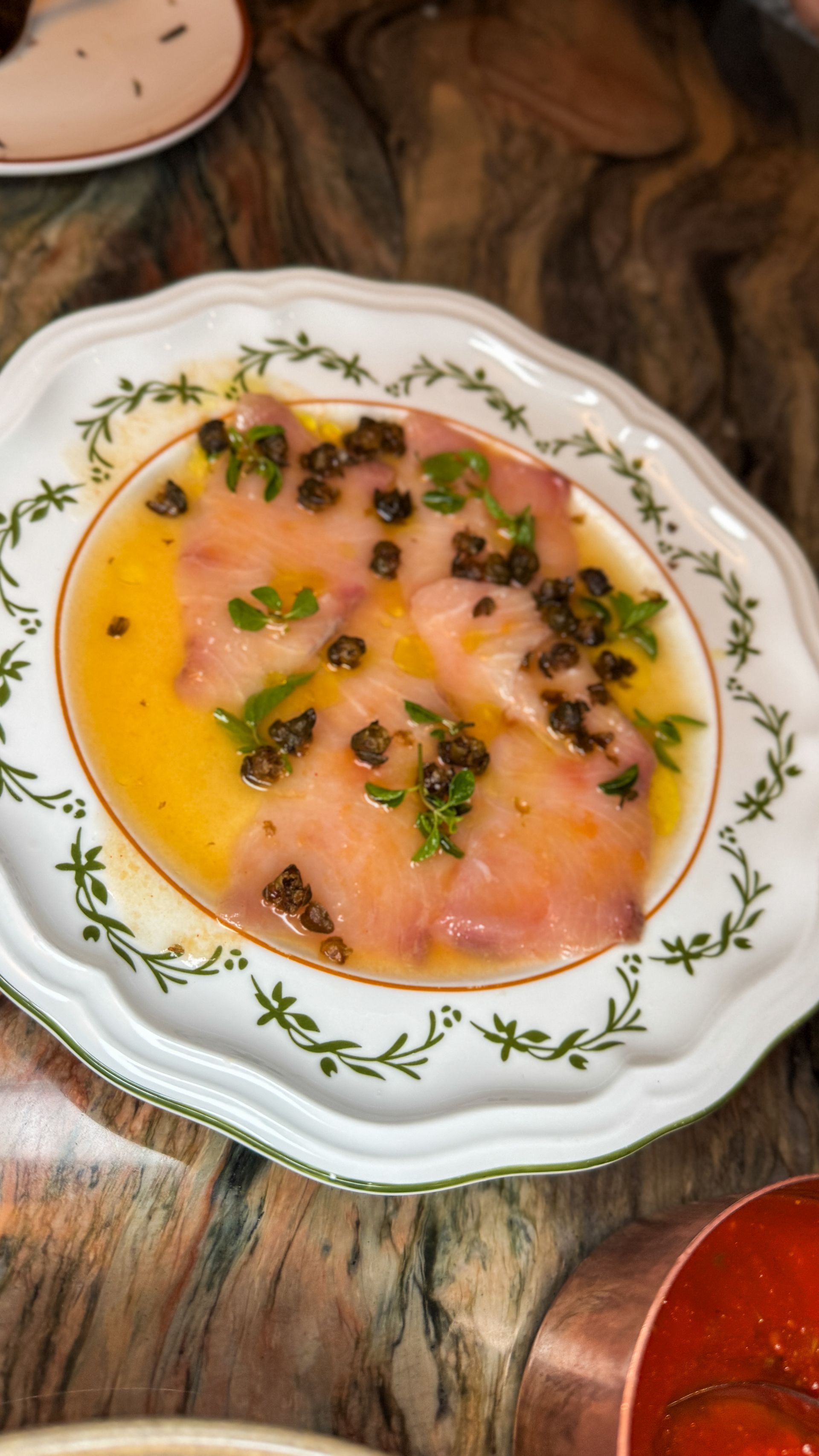 Herbed salmon tartare on a white floral plate with olive oil