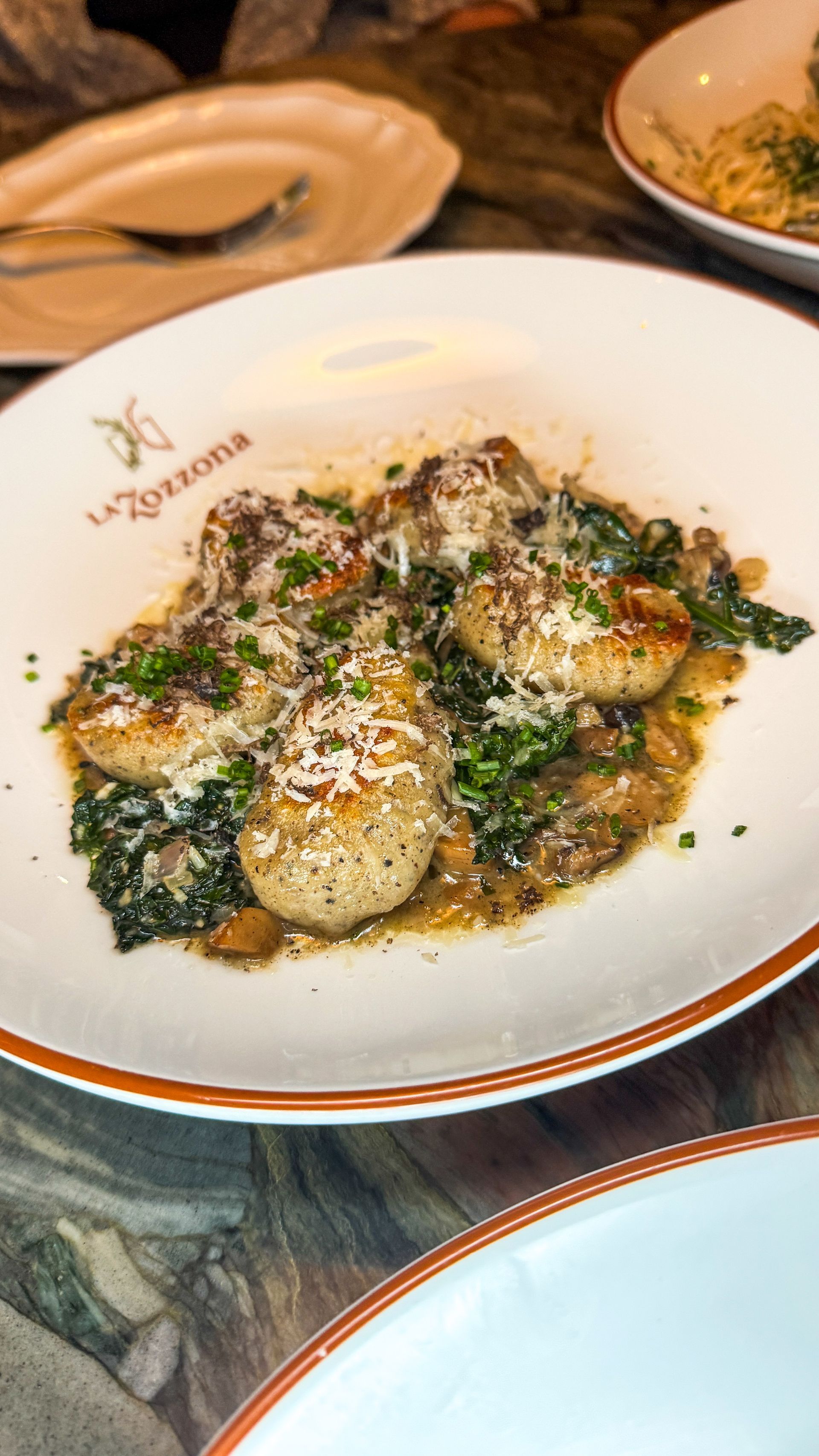 Plated herb-crusted scallops on greens at a restaurant table