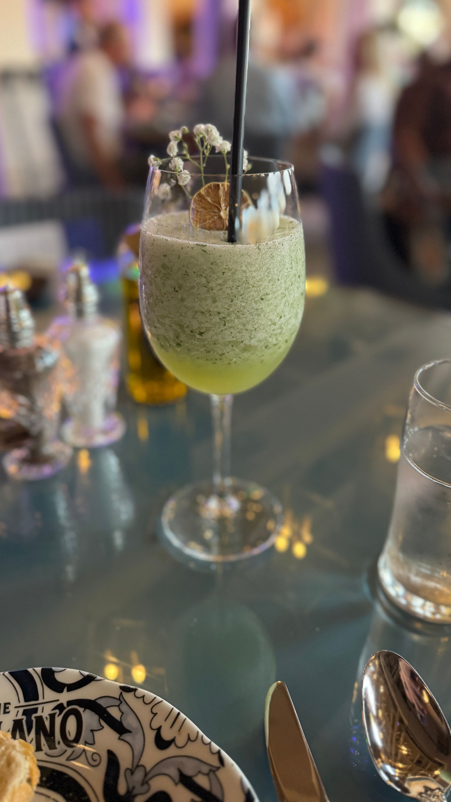 A close up of a drink in a wine glass on a table.